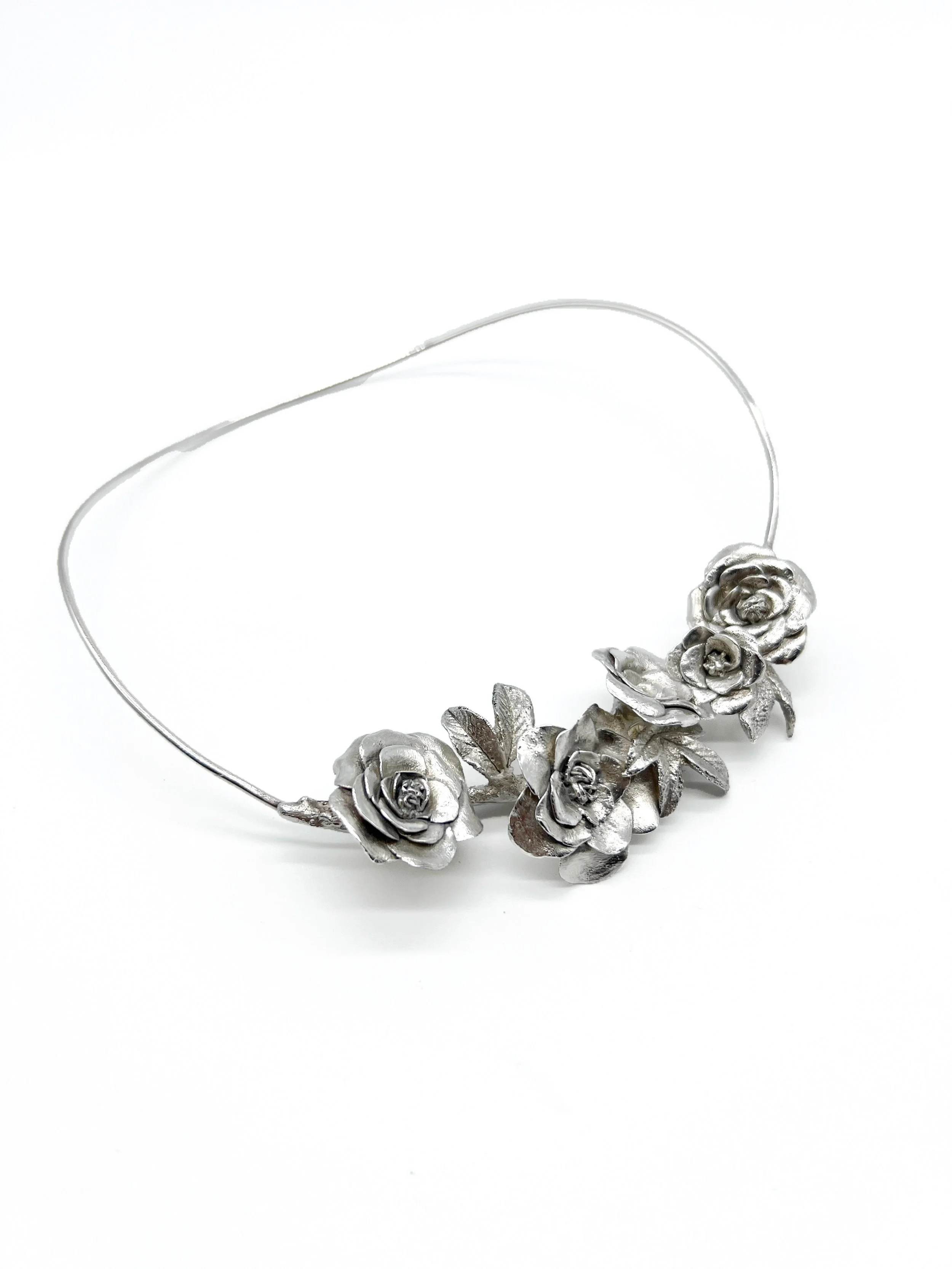 Silver floral necklace with roses and leaves on a white background.