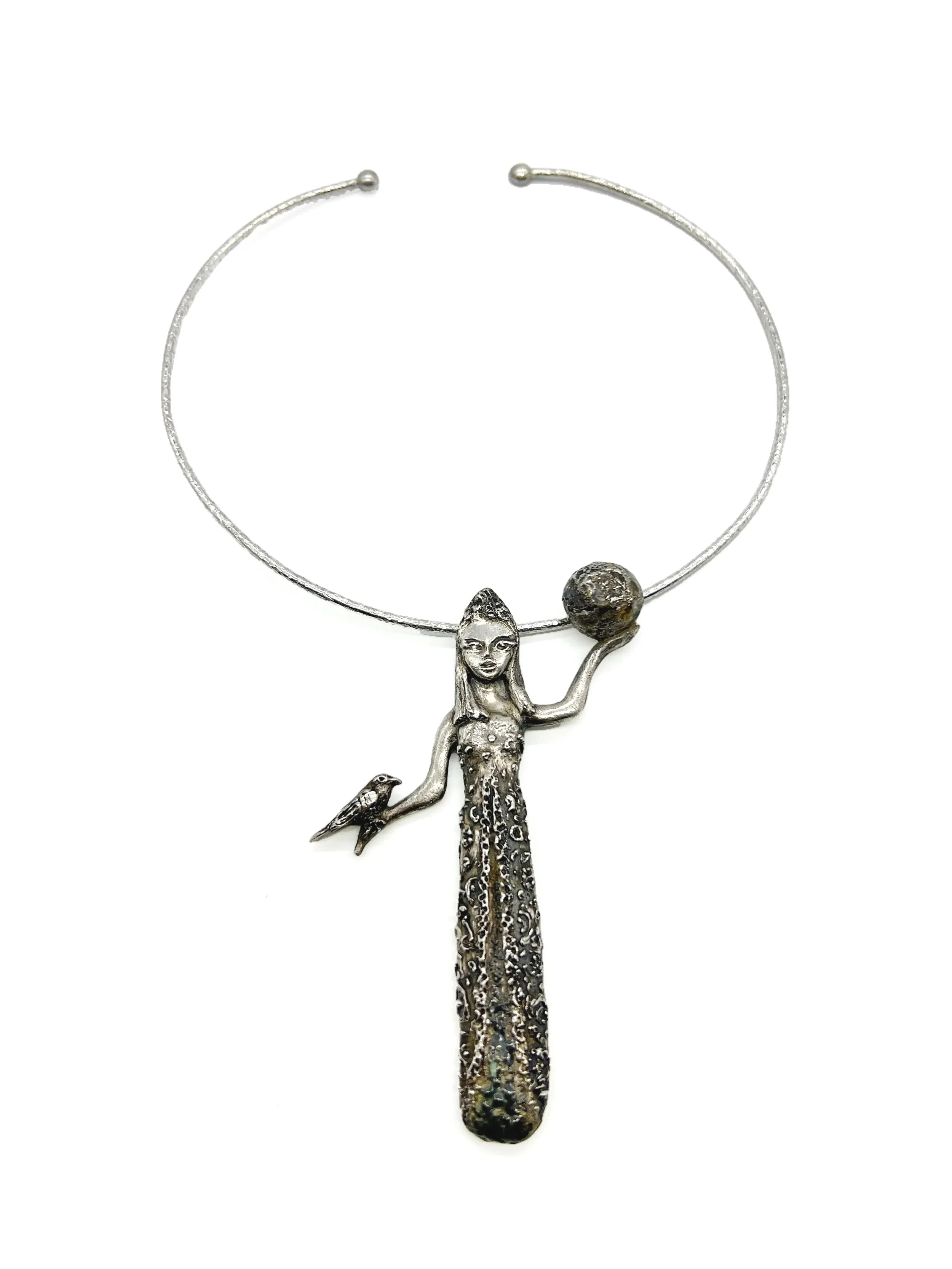Silver necklace with a pendant of a woman holding a globe, a bird on her hand, and a long textured chain.