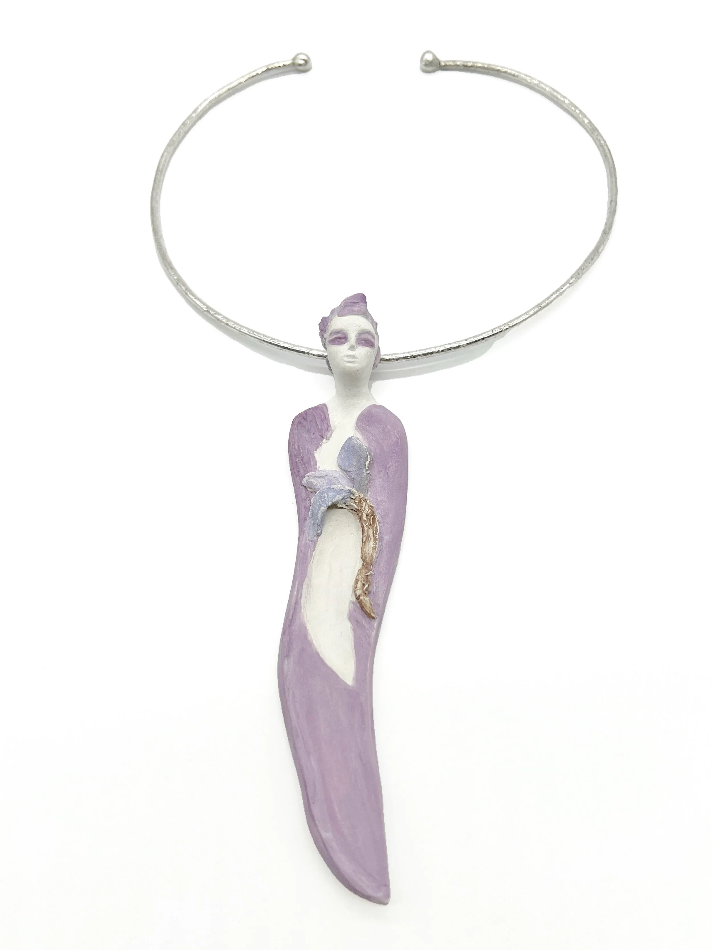 A silver bracelet with a purple and white painted figure of a woman attached to it.
