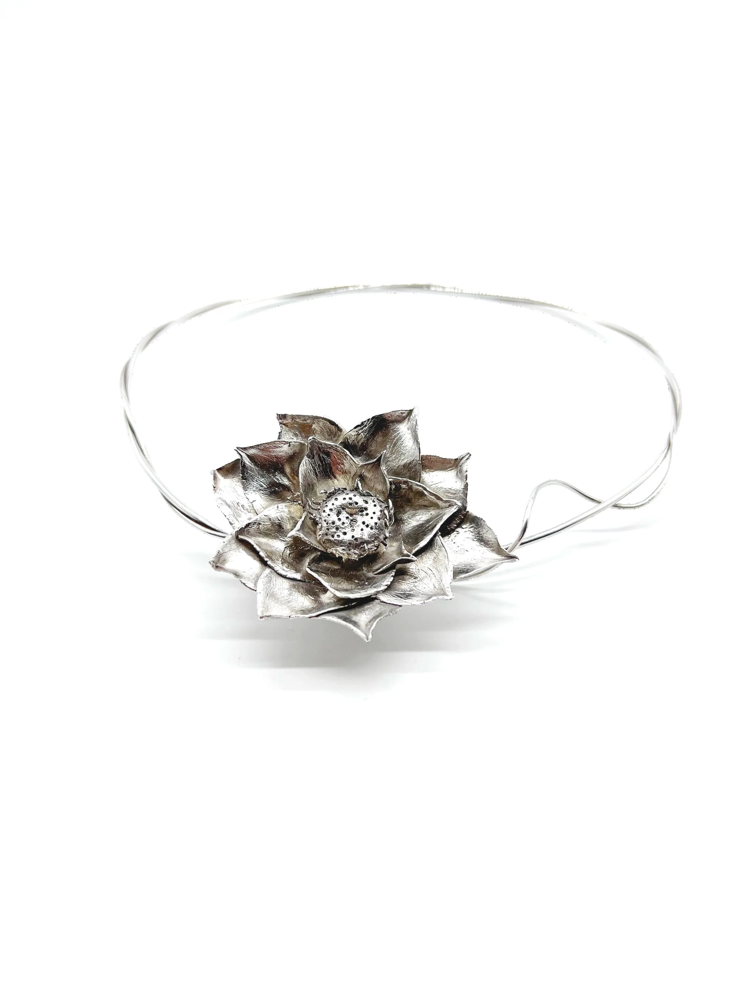 A silver decorative tray in the shape of a flower with petals and a small lotus flower in the center, set against a white background.