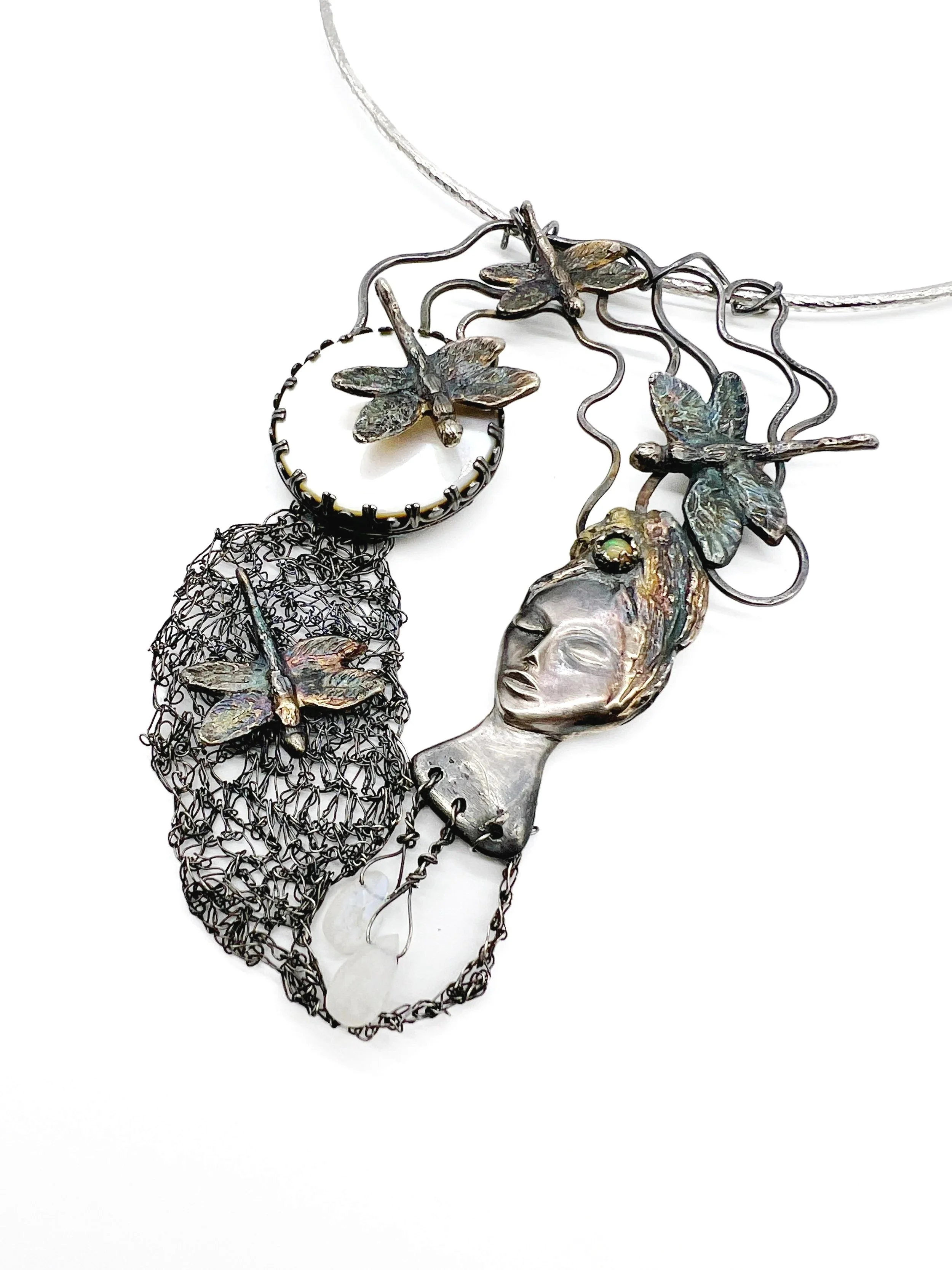 Jewelry necklace with leaf and face pendant, featuring metal flowers and wire mesh details.