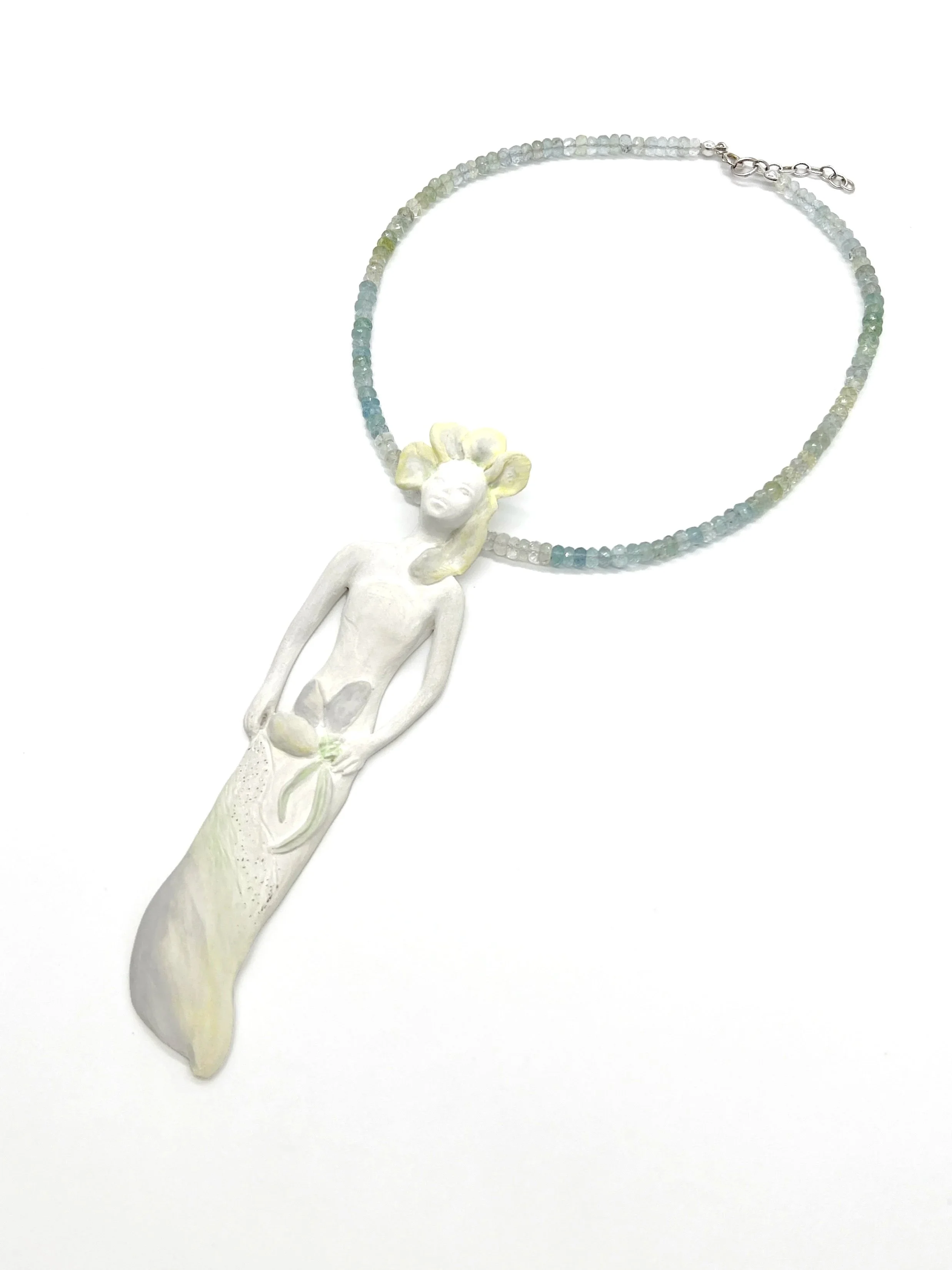 A necklace with small, multicolored beads and a large white 3D sculpture of a woman with mouselike ears as a pendant.