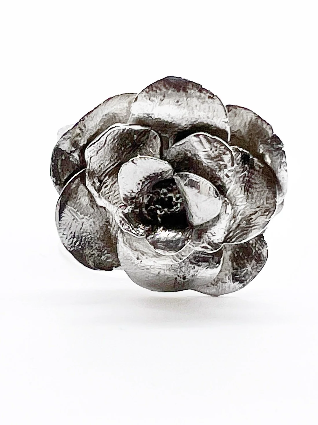 A metallic flower sculpture made of shiny, reflective metal with detailed petals against a plain white background.