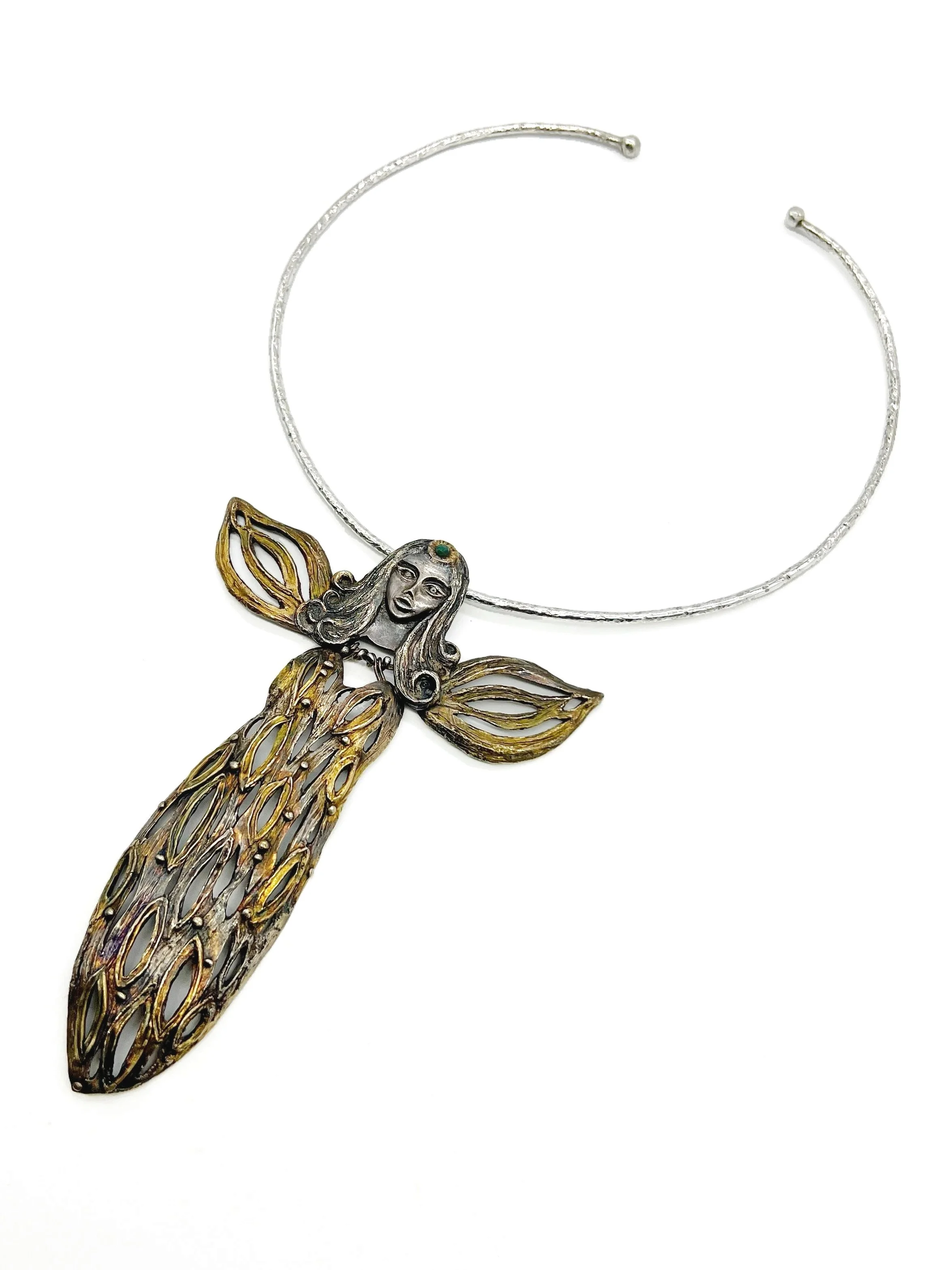 A decorative necklace featuring a fairy with a silver face, green eyes, and golden hair and wings, on a white background.