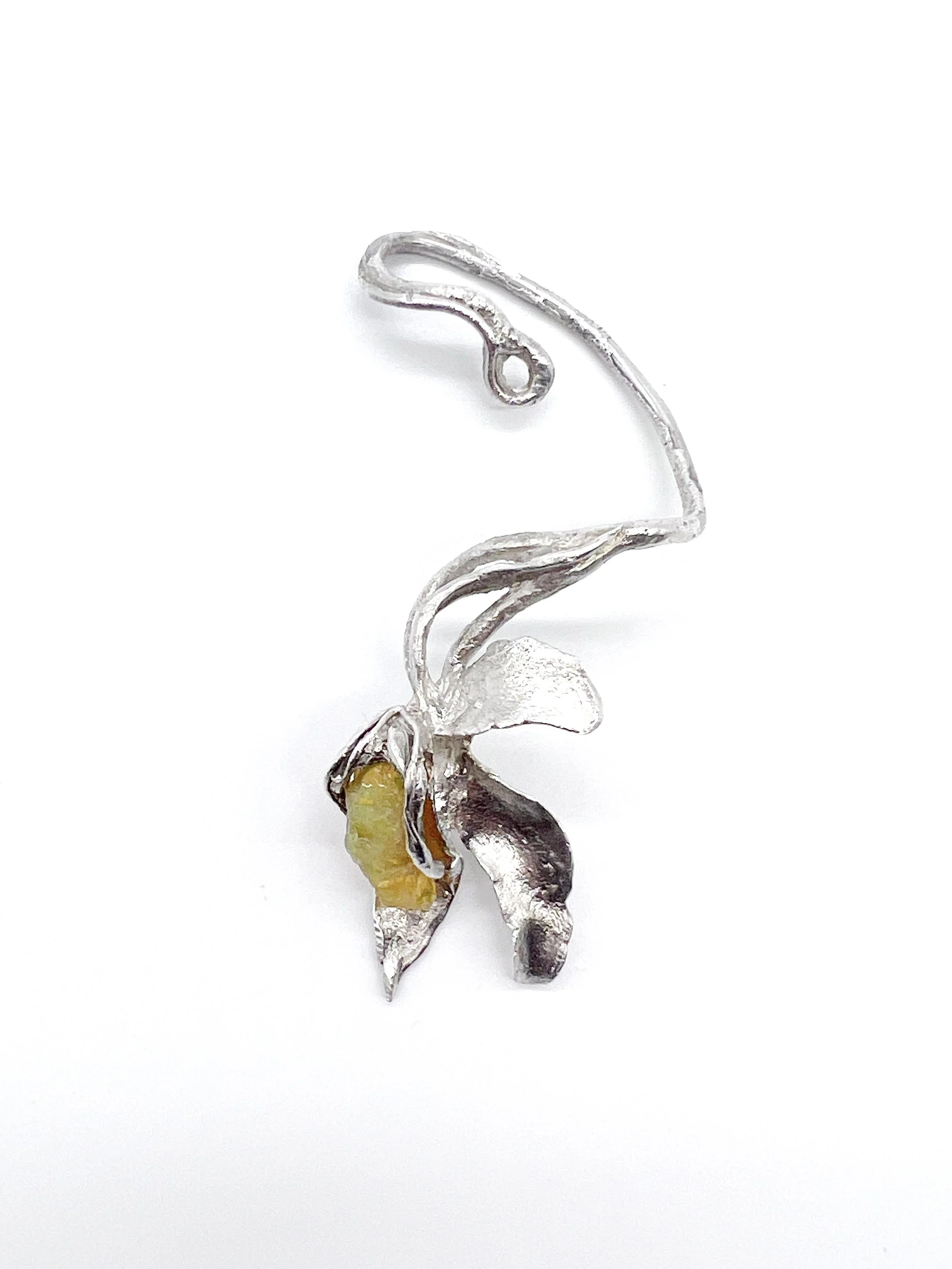 A decorative jewelry piece resembling a flower with clear and yellowish stones set in silver metal, on a white background.