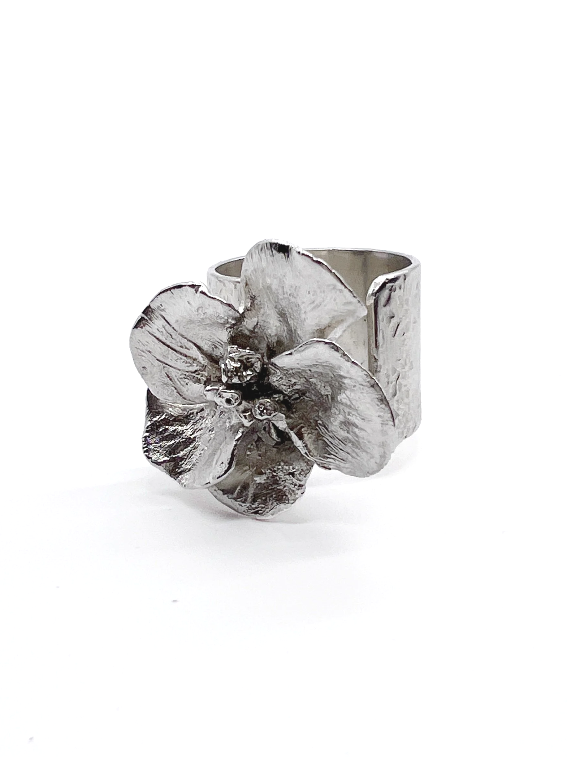 Silver ring with a large flower design on top, set against a plain white background.