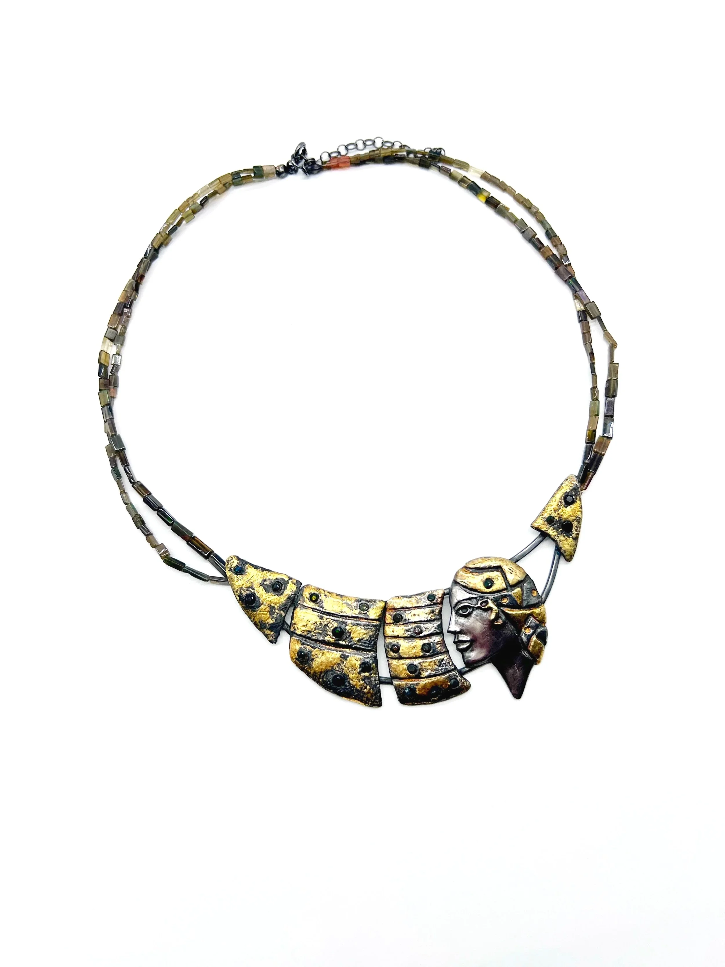 Gold necklace with a pendant shaped like a smiling woman's face with curly hair and a decorative crown.