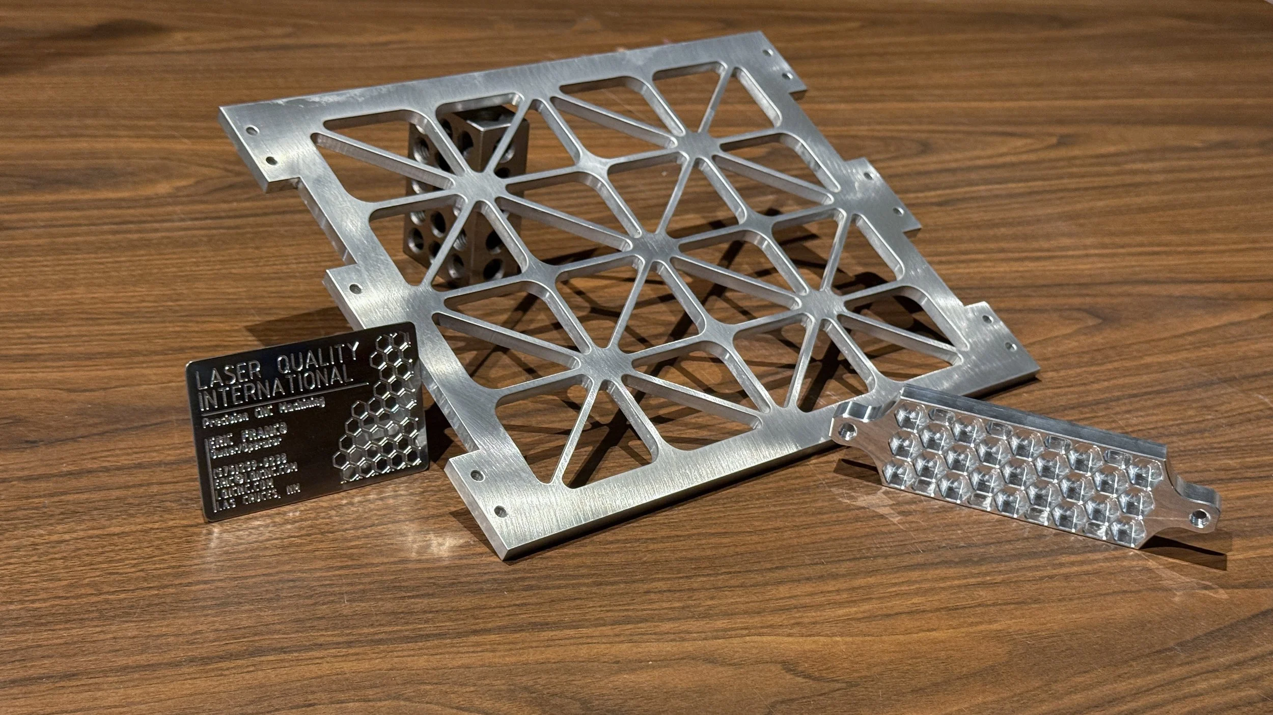 Custom machined isogrid panel, honeycomb component, and engraved Laser Quality International business card.