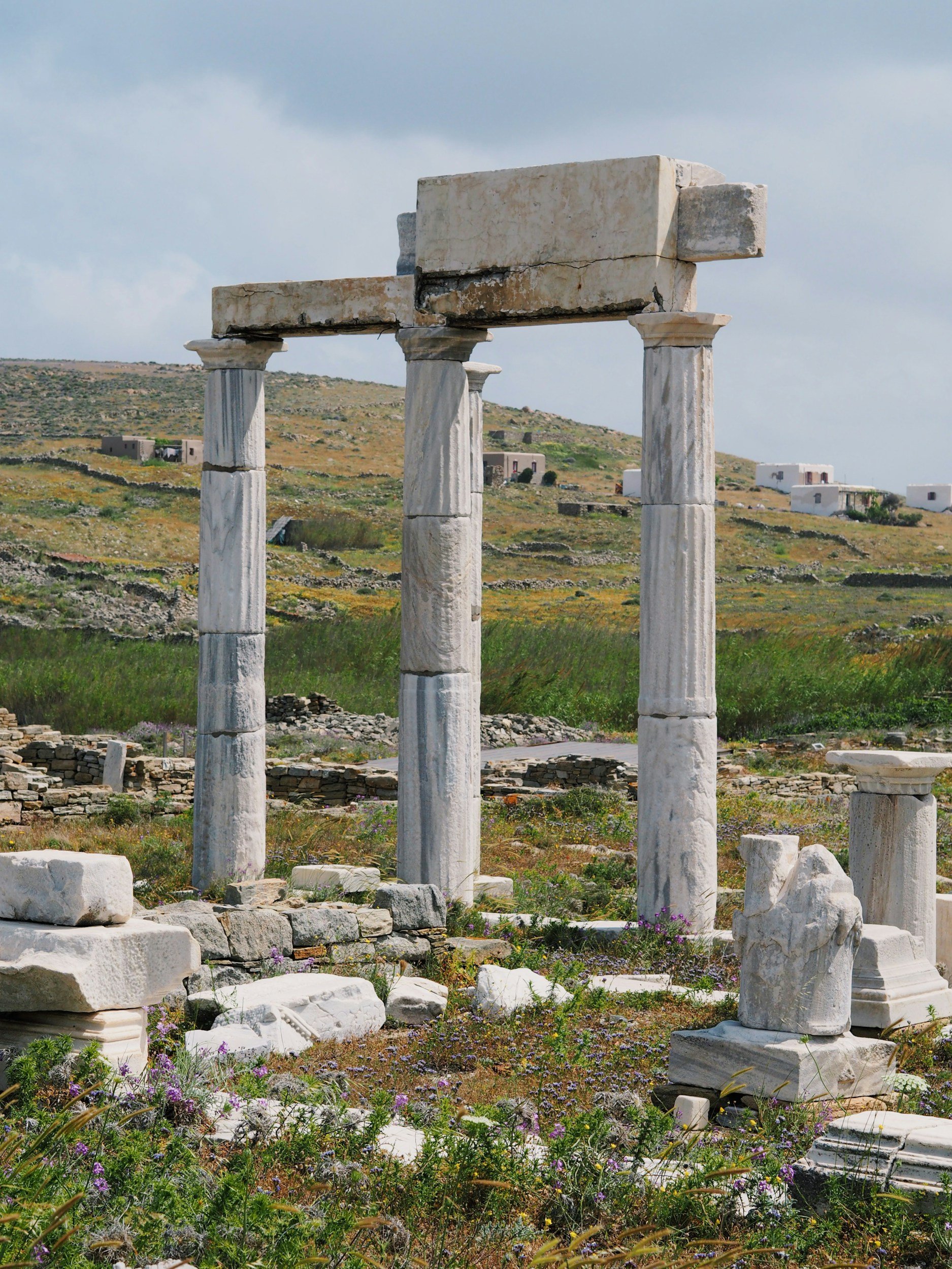 Ancient stone columns and ruins on a grassy hillside.