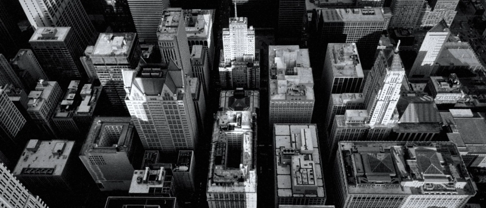 Black-and-white aerial view of dense downtown skyscrapers and city rooftops