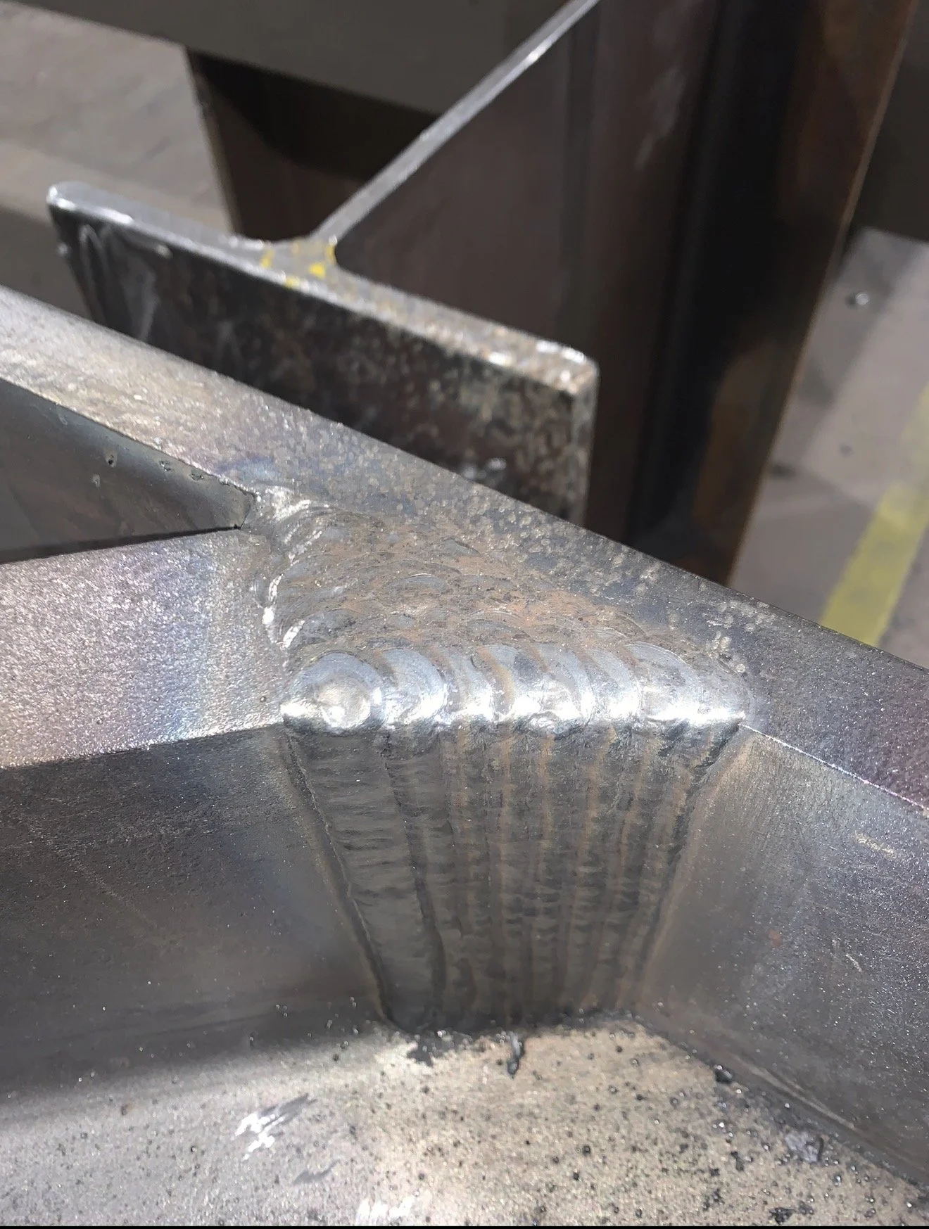 Close-up view of a welded metal joint, showing a bead along the weld seam on a steel structure.