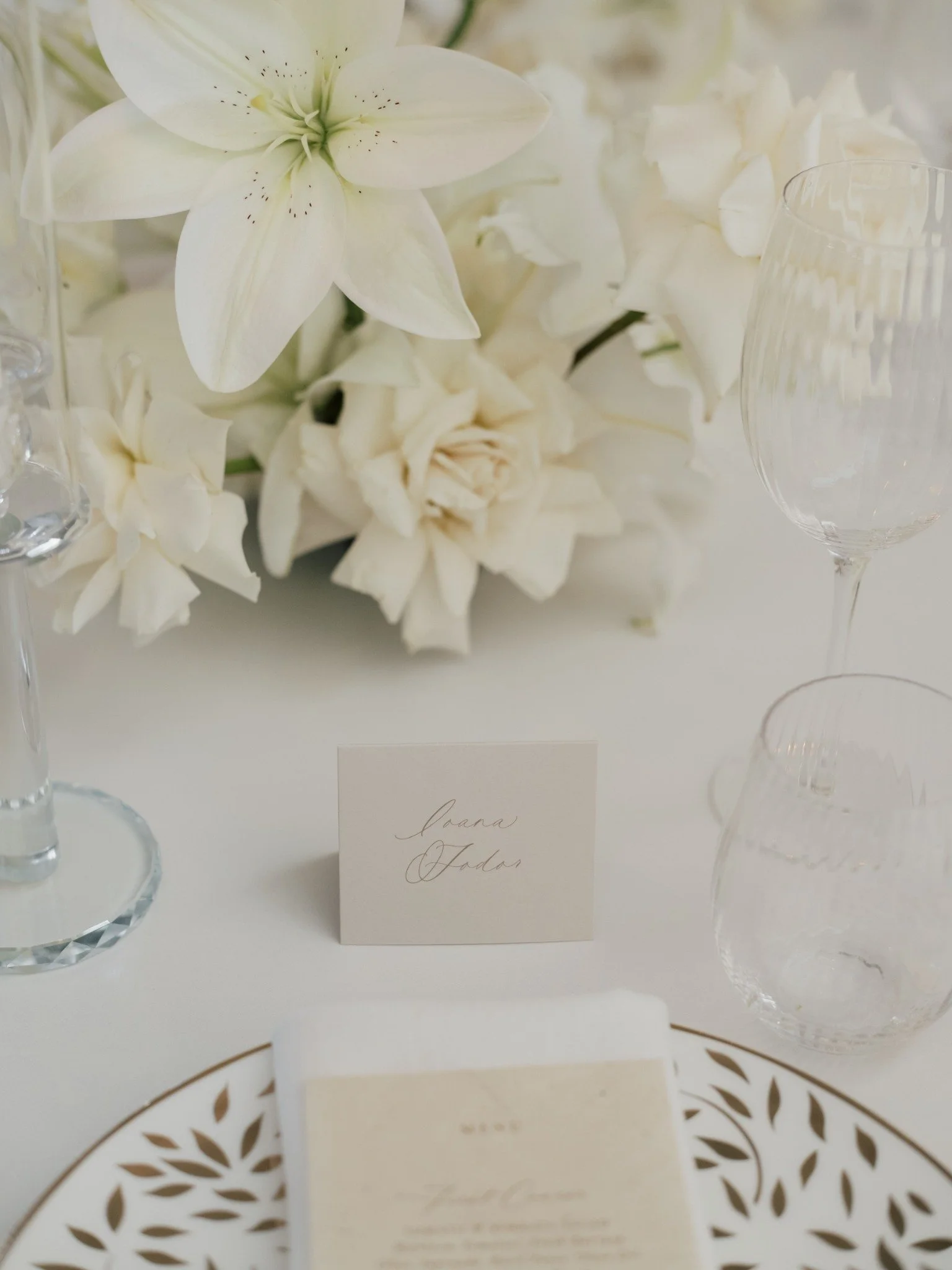 Close-up of white flowers and elegant place cards on a table at a wedding reception.