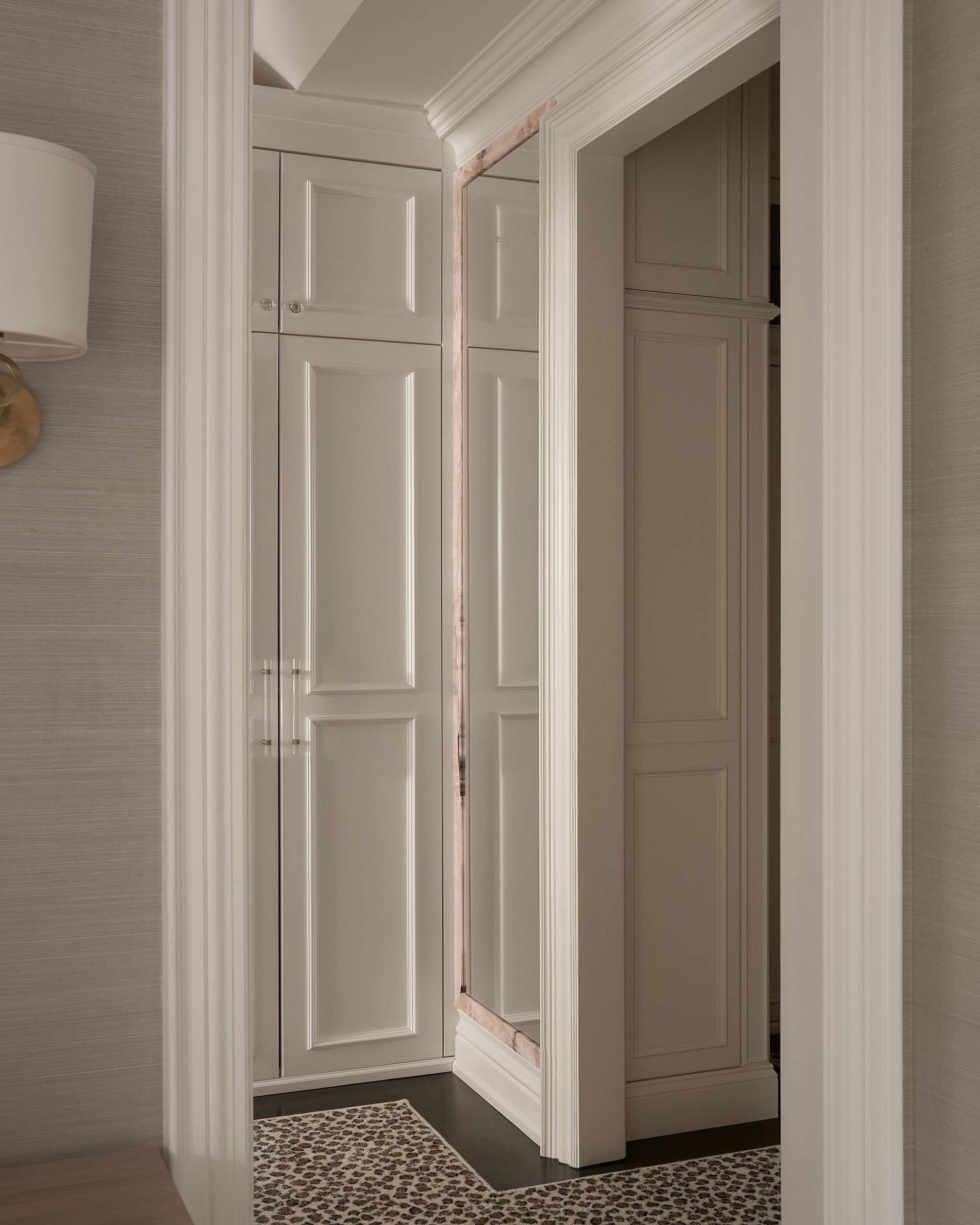 Inside view of a closet or wardrobe with white paneled doors and trim, with a decorative leopard-print rug in the foreground.