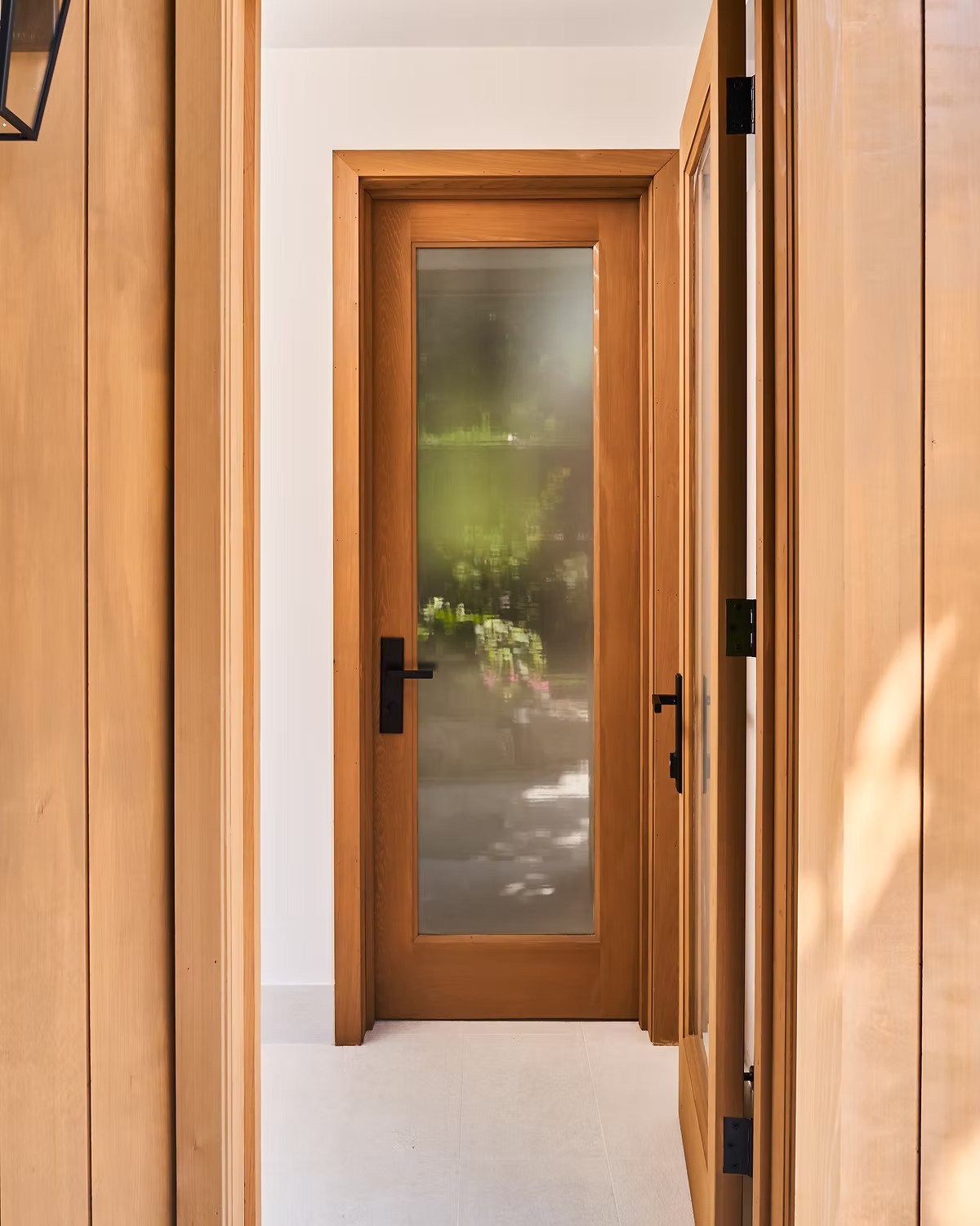 Image of a wooden door with frosted glass window and black handle, surrounded by wooden wall panels.
