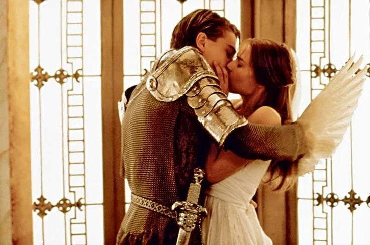 A knight and angel embracing before gilded doors in Romeo + Juliet