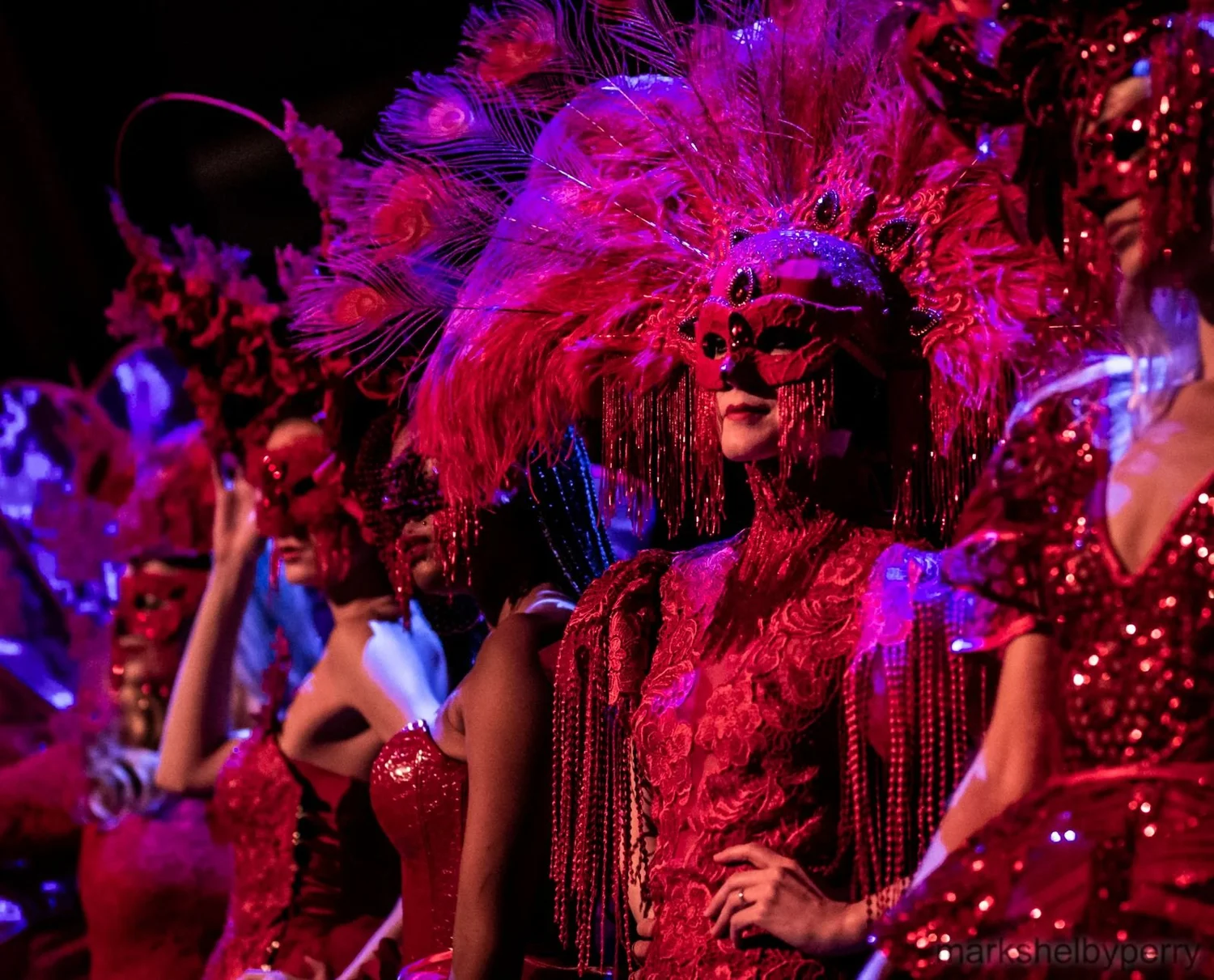 Red-masked ensemble in elaborate headdresses. Past Astarte Creative performance.