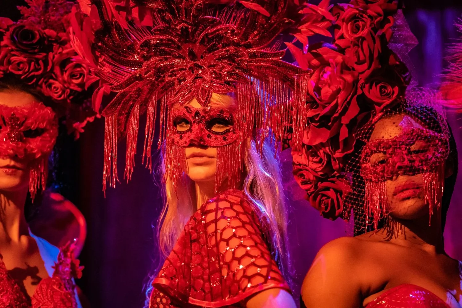 Masked trio in red floral headdresses. Past Astarte Creative performance.