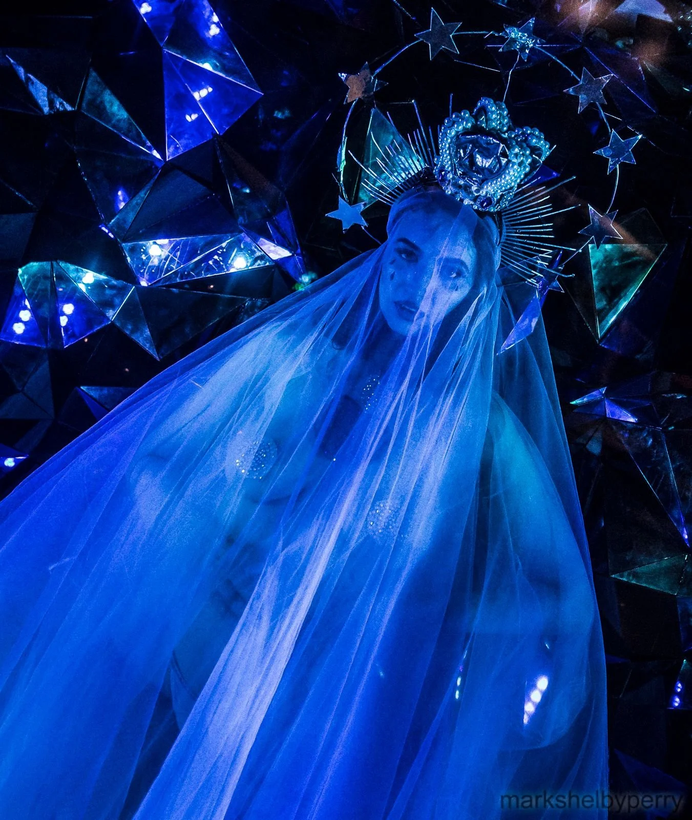 Close-up of a blue-veiled figure. Past Astarte Creative performance.
