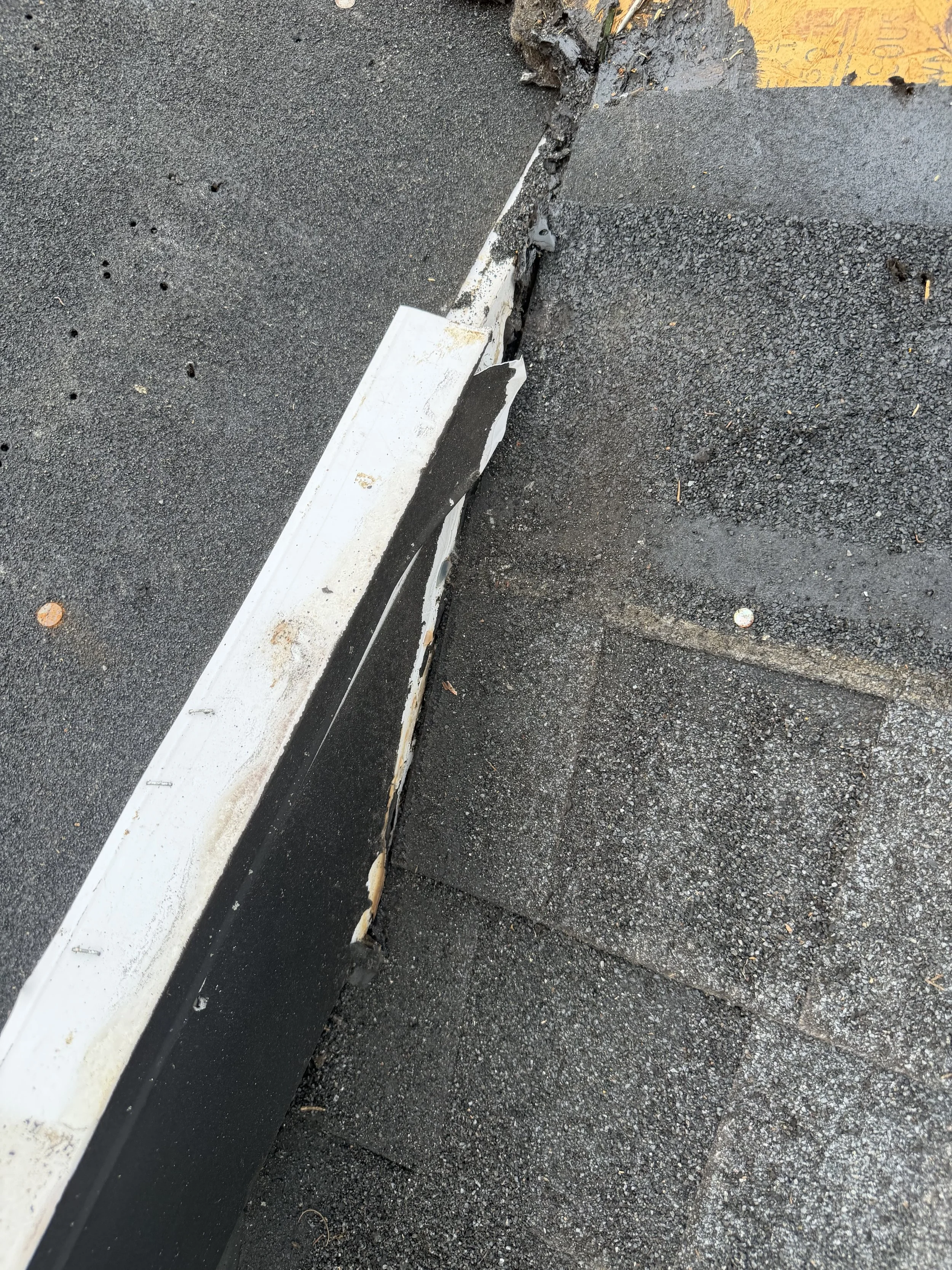 Damaged curb edge with broken asphalt and peeling paint on curb