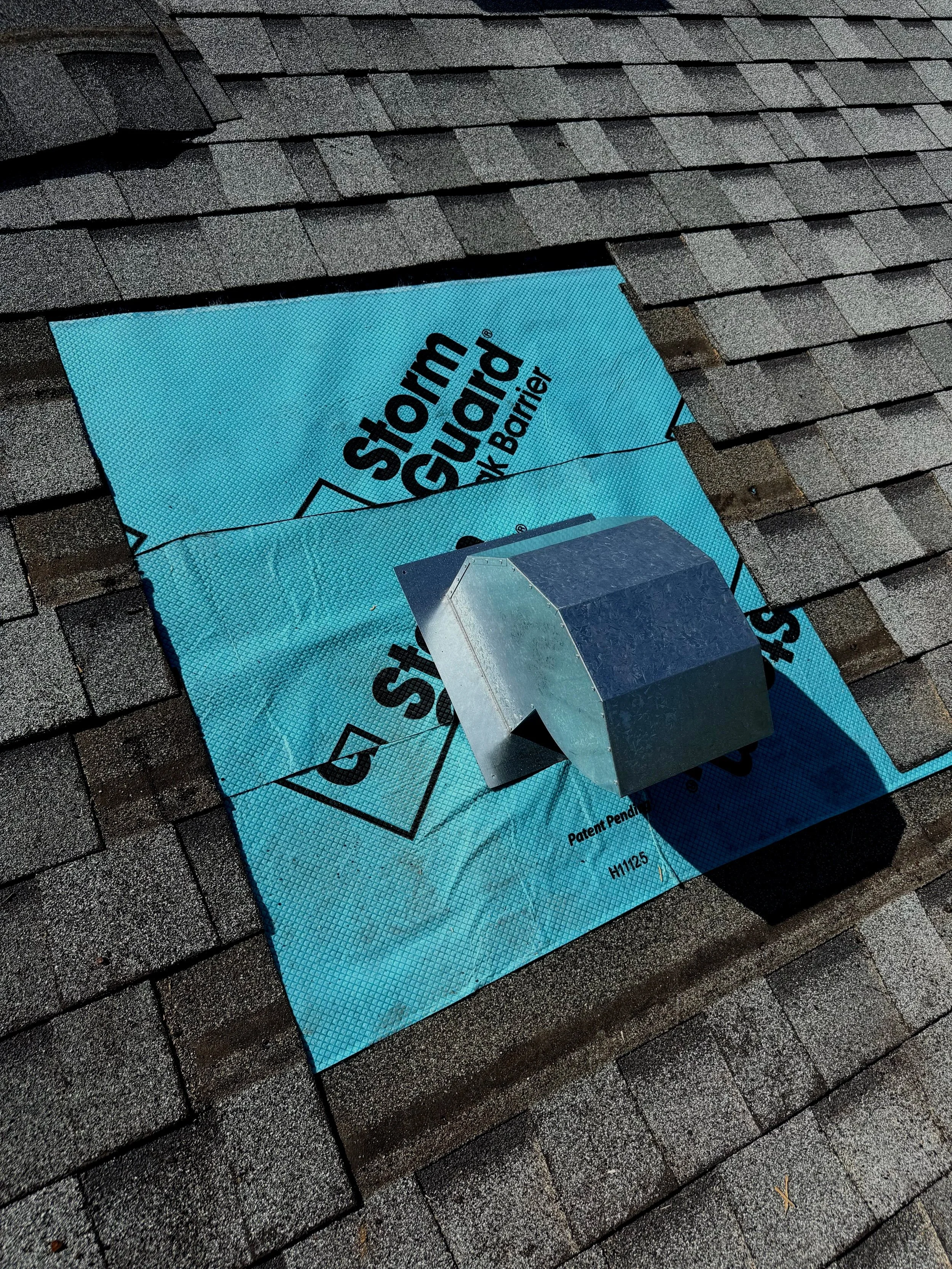 Roof with shingles, blue underlayment labeled 'Storm Guard', and vent pipe protruding from the roof.