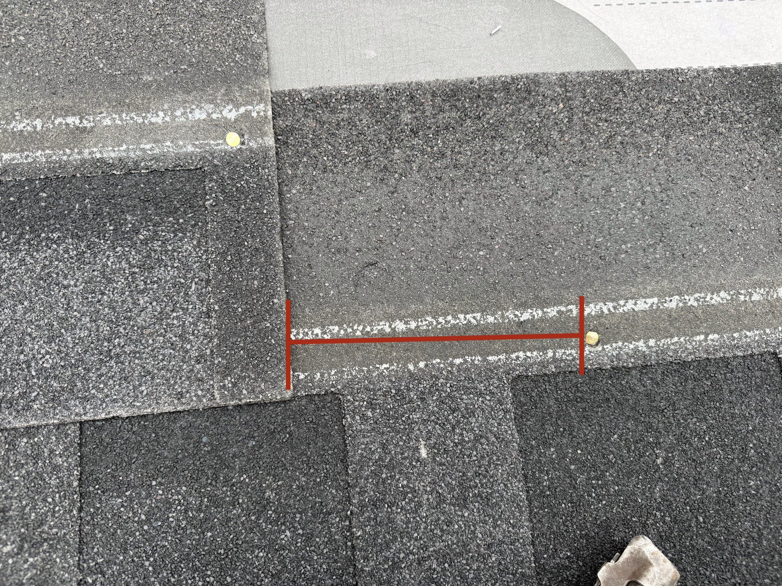Close-up of a section of asphalt road with a white line and a white curb edge. There is a small yellow object on the road near the curb.