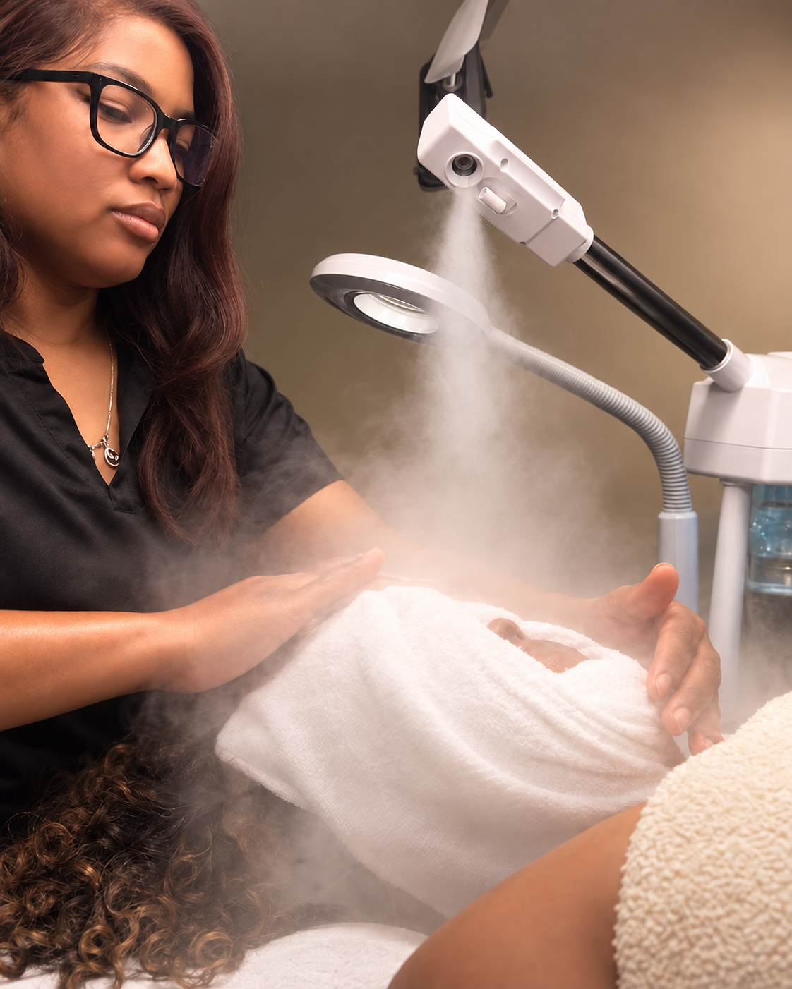 A beautician performing a steam facial treatment on a client at a spa or clinic, with steam rising from the treatment.