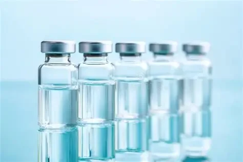 Five small glass vials containing clear liquid, arranged in a row against a light blue background.