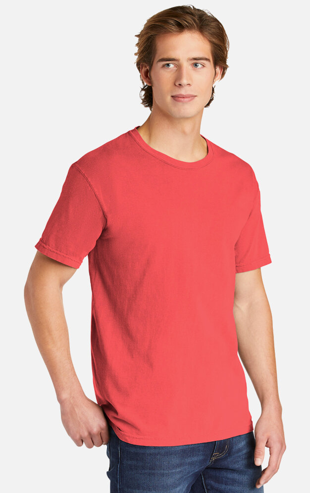Young man with brown hair wearing a red t-shirt and blue jeans looking slightly to the side.