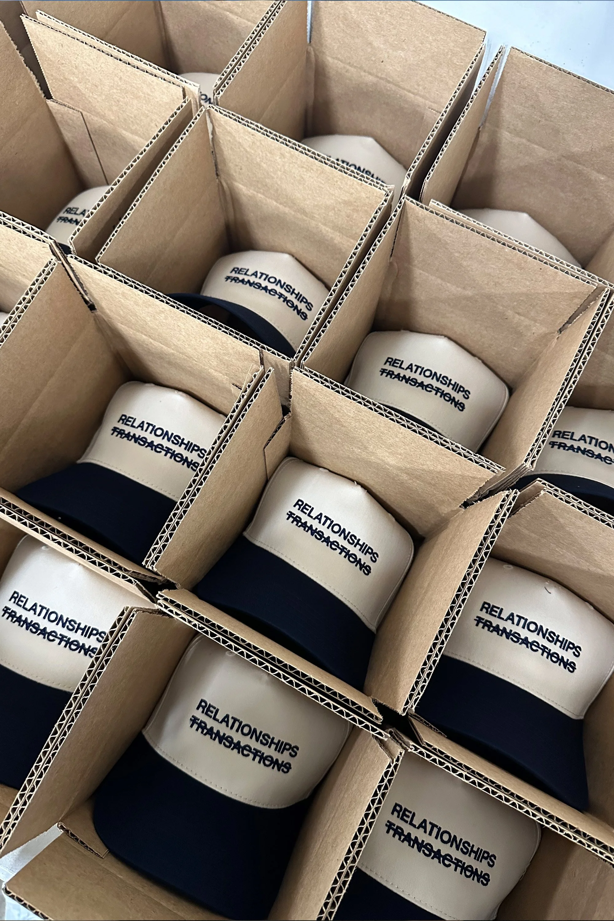Multiple white mugs with black handles, each labeled with the text 'RELATIONSHIPS TRANSFORM' in black, organized inside individual cardboard boxes.