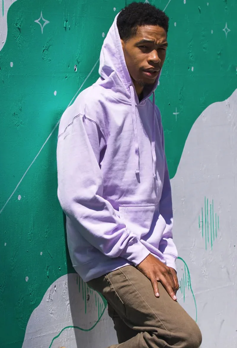 Young man in a lavender hoodie leaning against a colorful mural wall.