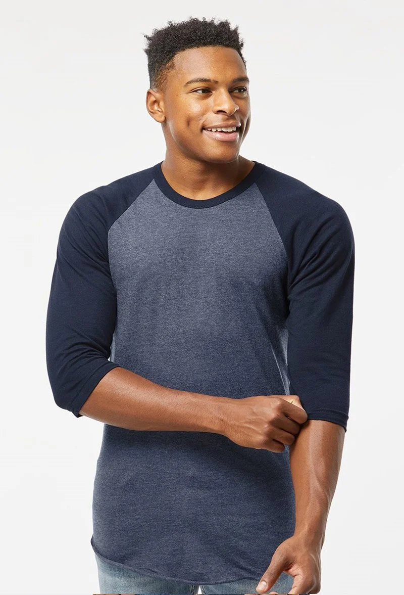 Young man smiling, wearing a navy and gray three-quarter sleeve shirt with a white background.