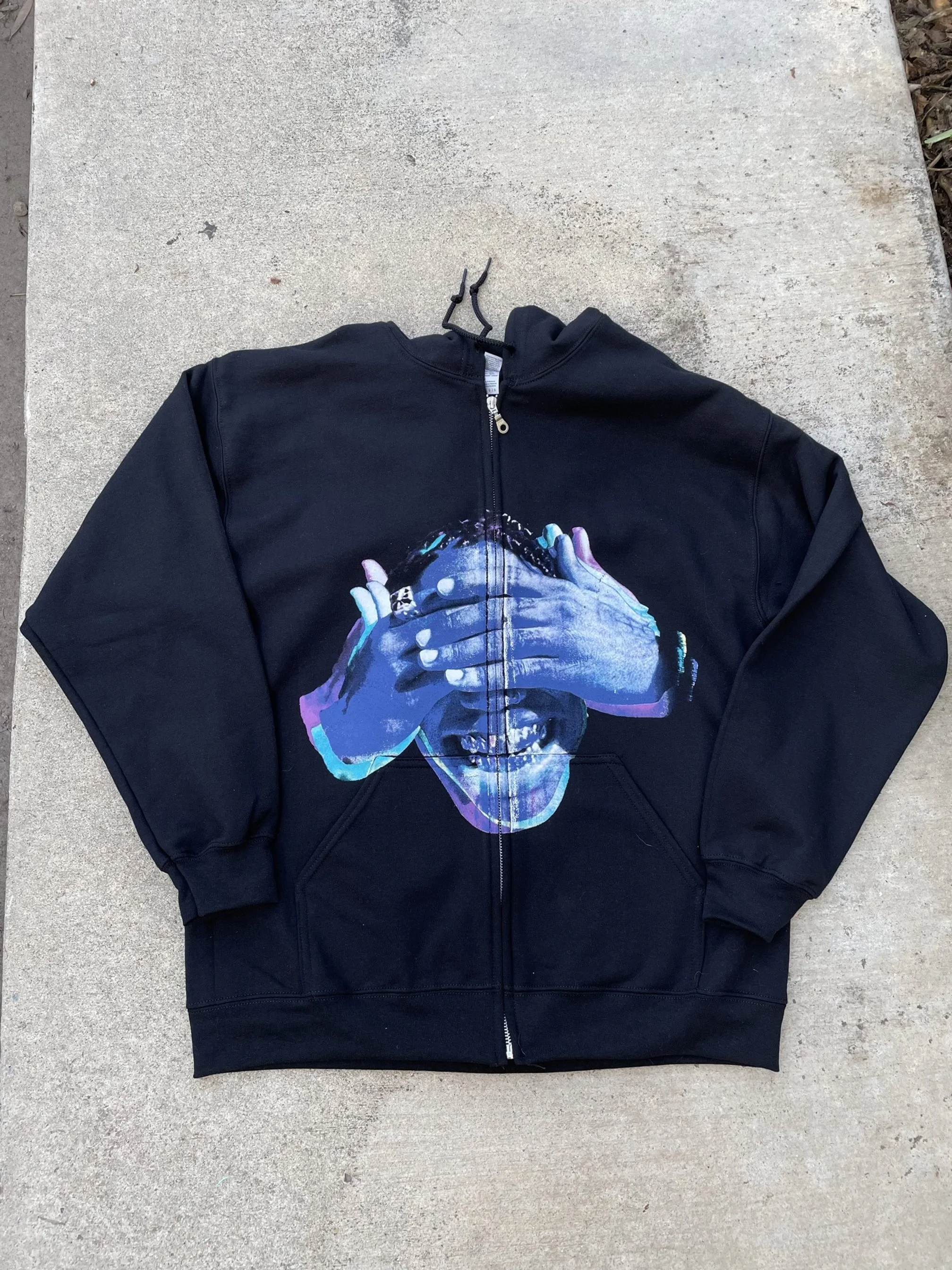Black zip-up hoodie with a colorful graphic of a woman covering her eyes with her hands, printed on the front.