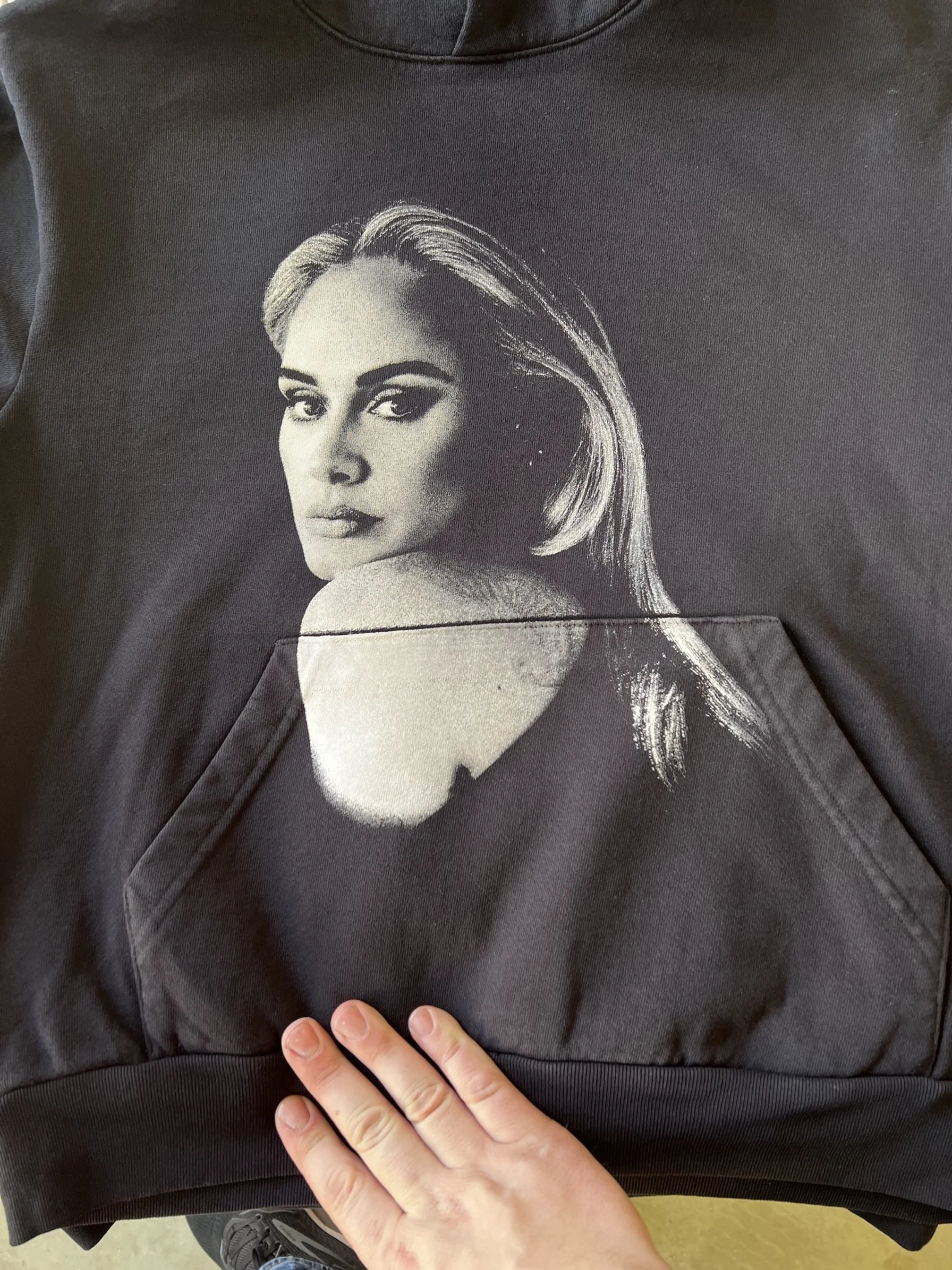 Black hoodie with a grayscale portrait of a woman with styled hair on the front pocket area.