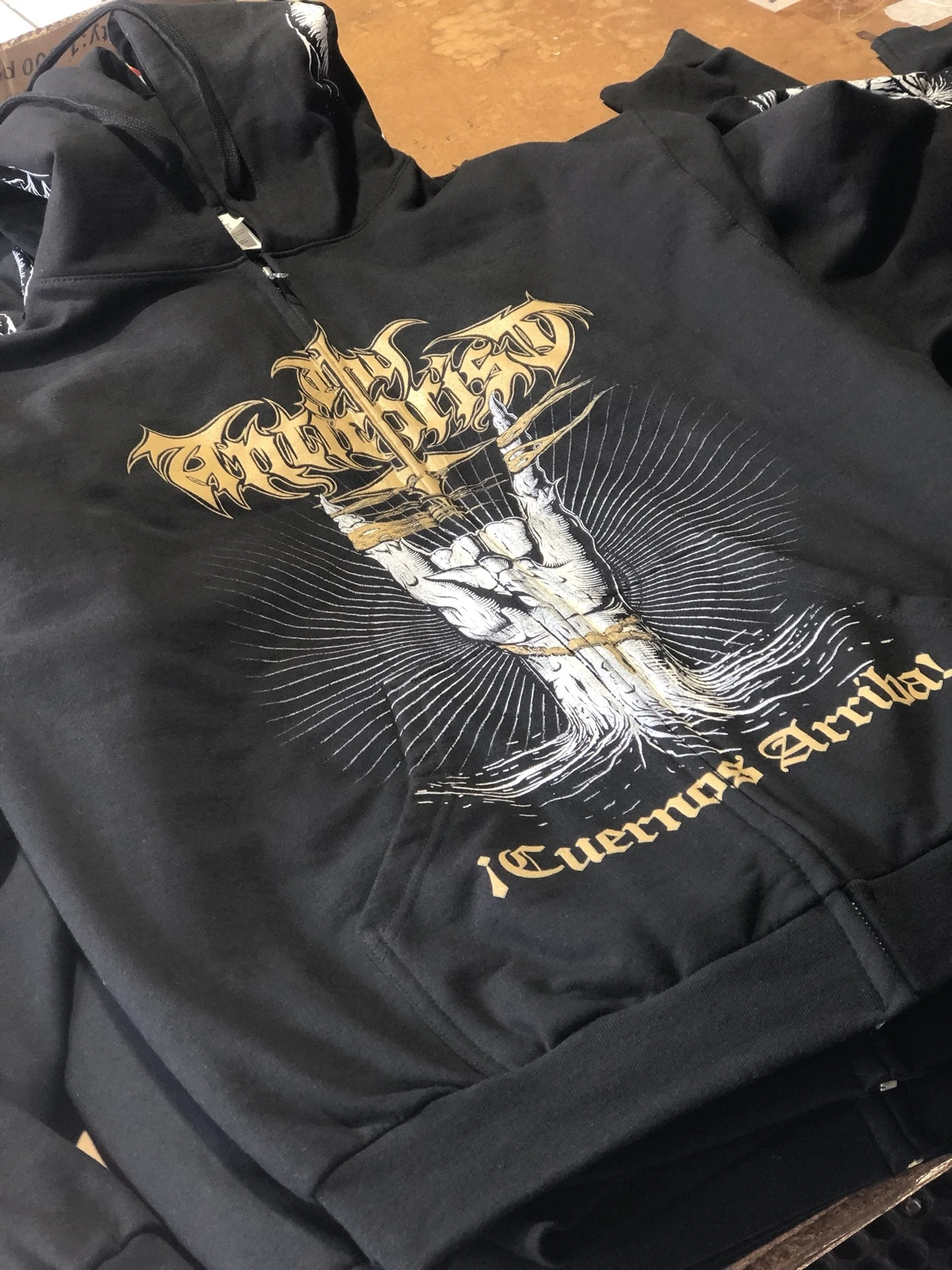 Black zip-up hoodie with a graphic design featuring a skeletal hand in a cup of water, radiating lines, and text reading 'Guerrera'.
