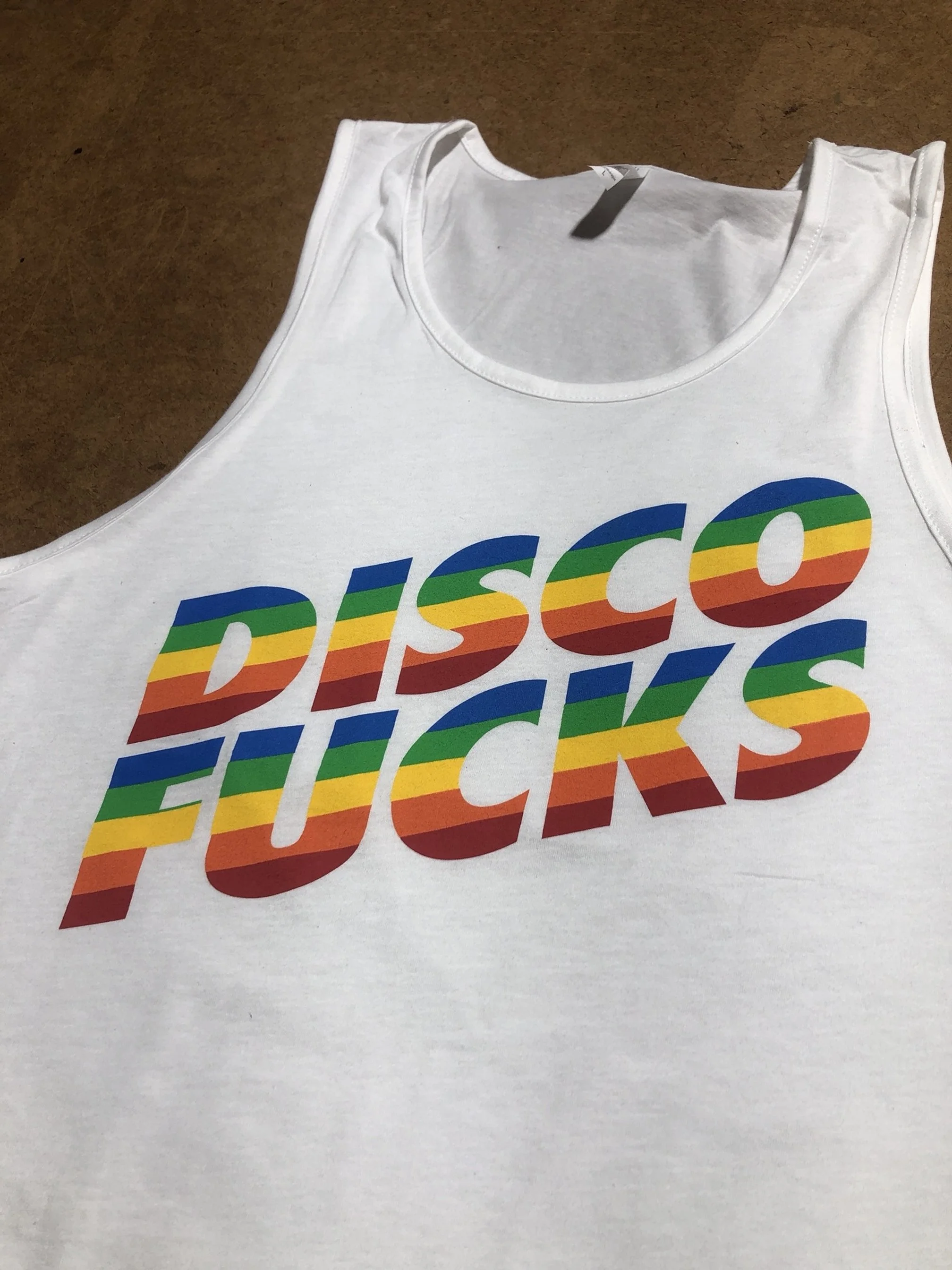 White tank top with rainbow-colored text that reads 'DISCO F***S' in bold letters.
