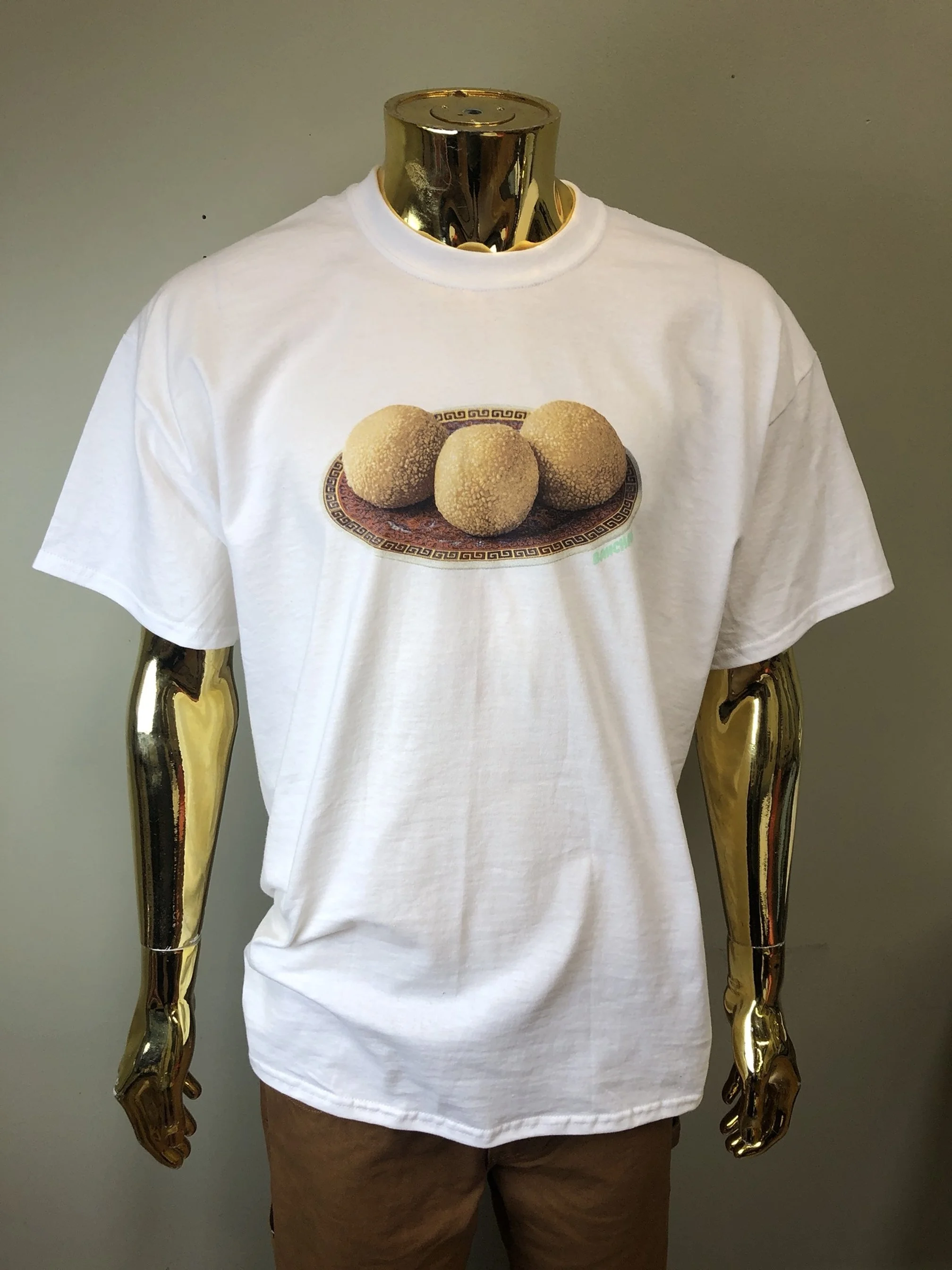 White T-shirt with a print of four sesame balls on a decorative plate.