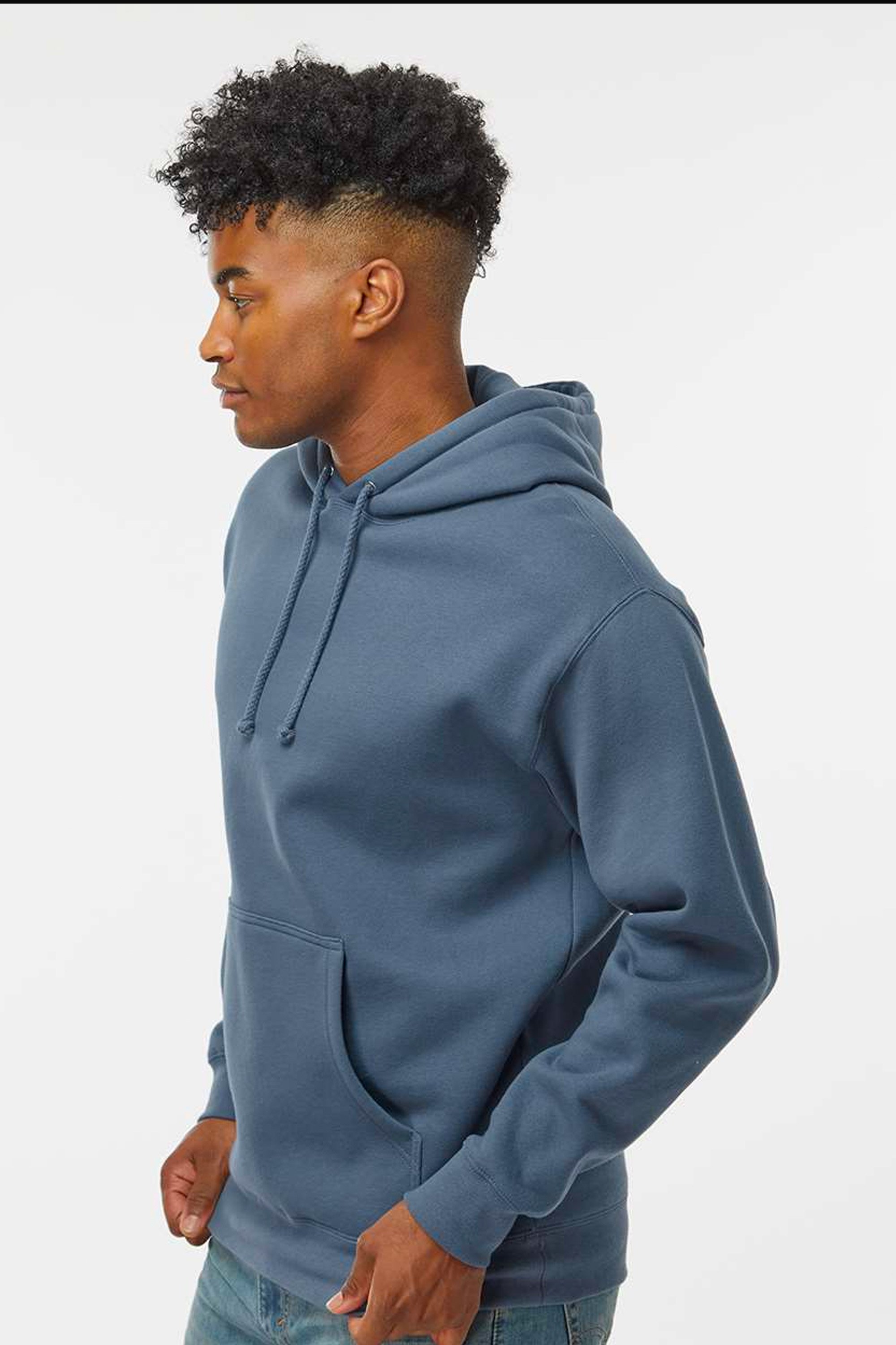 Young man wearing a blue hoodie with a front pouch pocket, standing in profile against a plain background.