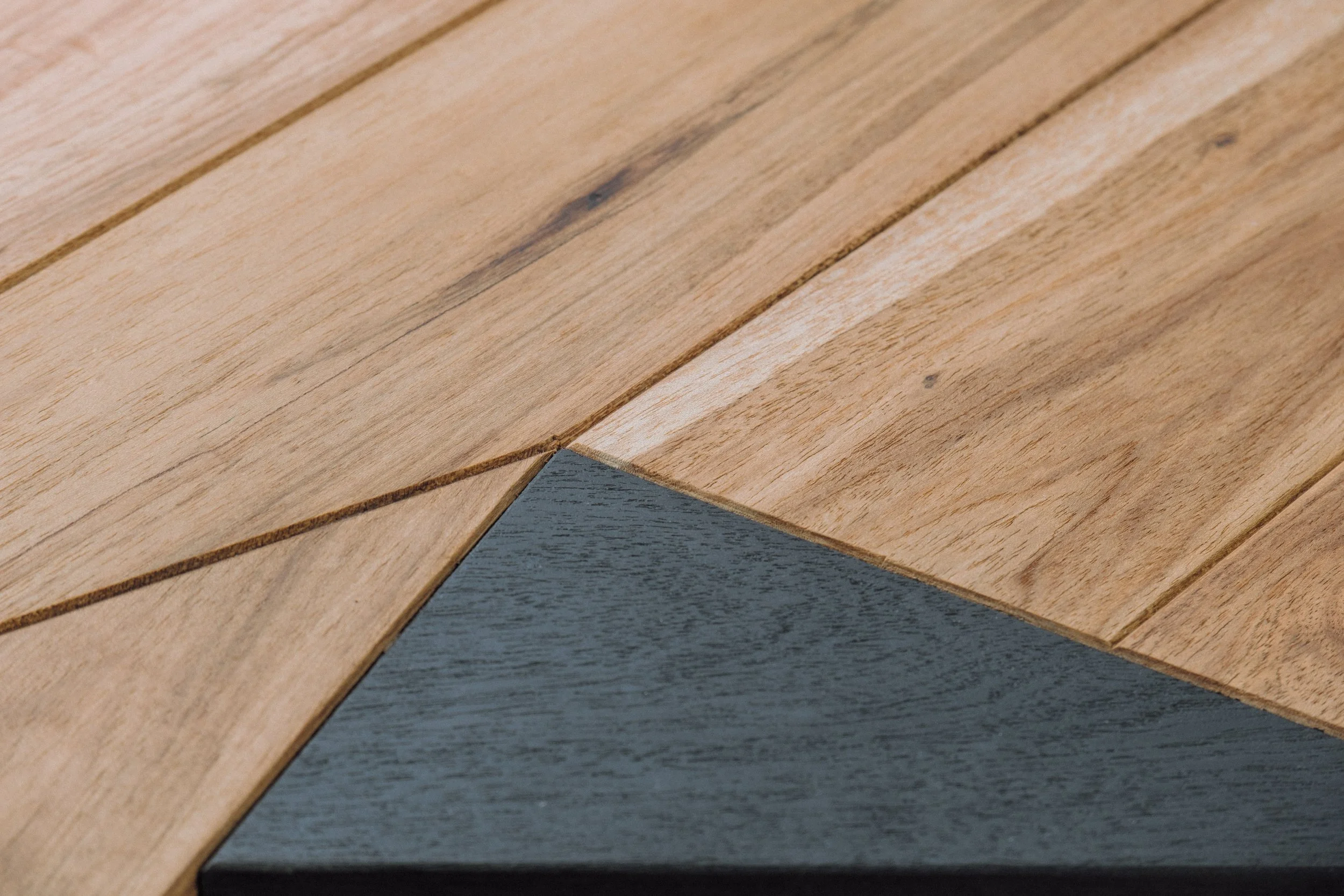 Plateau de bureau montrant le travail du bois et des veinages, contrasté par une planche de bois massif teint.