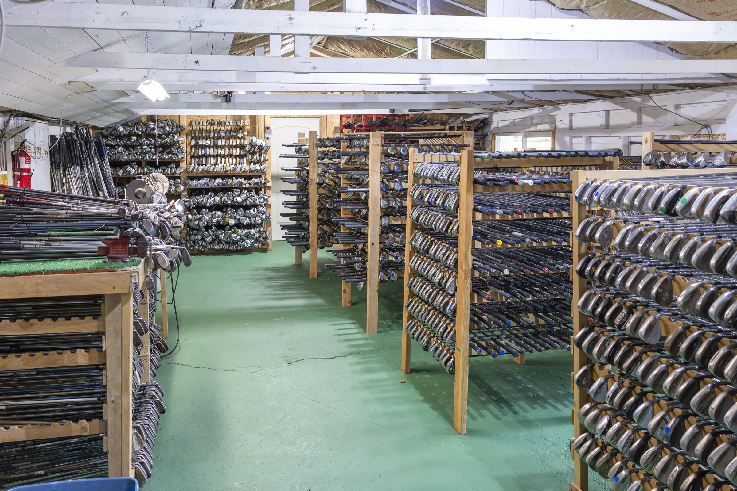 Rows of wooden racks holding hundreds of donated golf clubs inside the Area 51 workshop