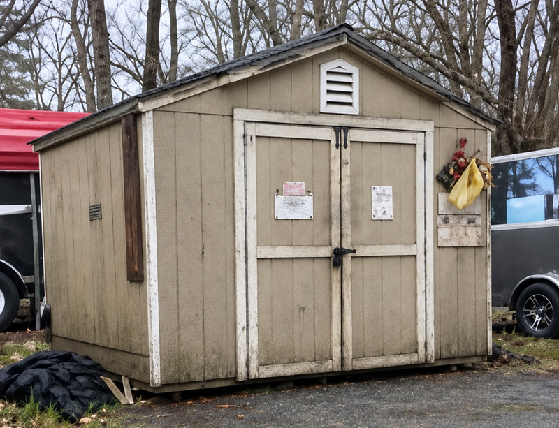 The current maintenance storage shed at ALVGC, a weathered wooden shed with double doors.