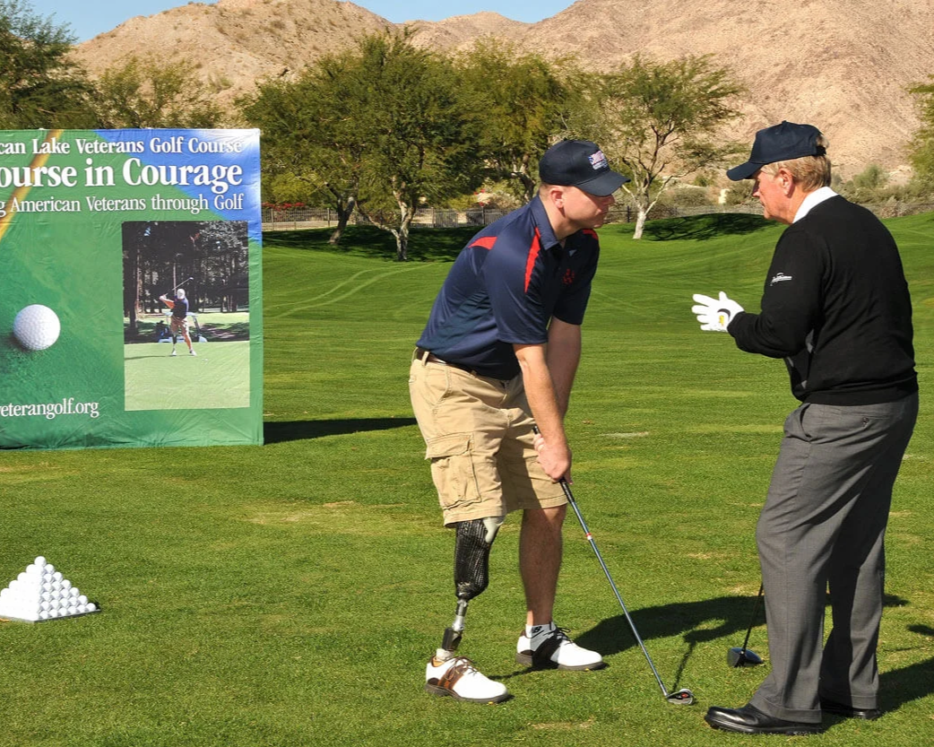 Two men talking on the golf course, one of whom has a prosthetic leg.