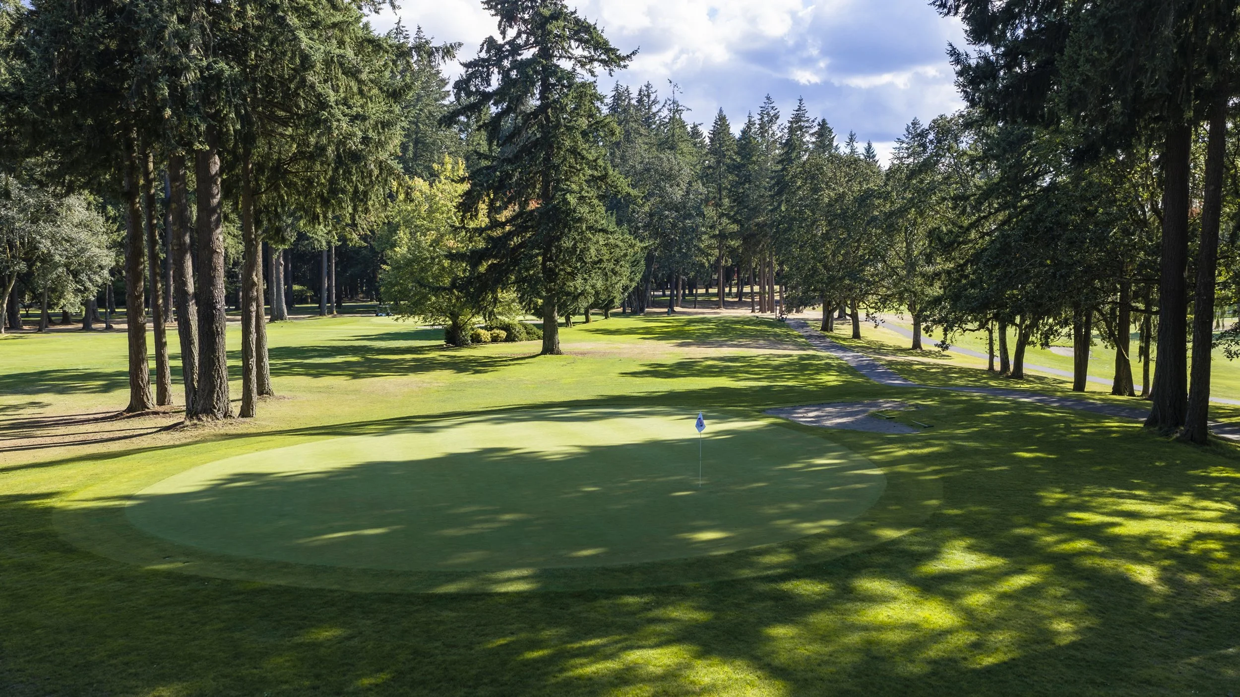 Hole 8 at American Lake Veterans Golf Course, a green ringed by tall trees.