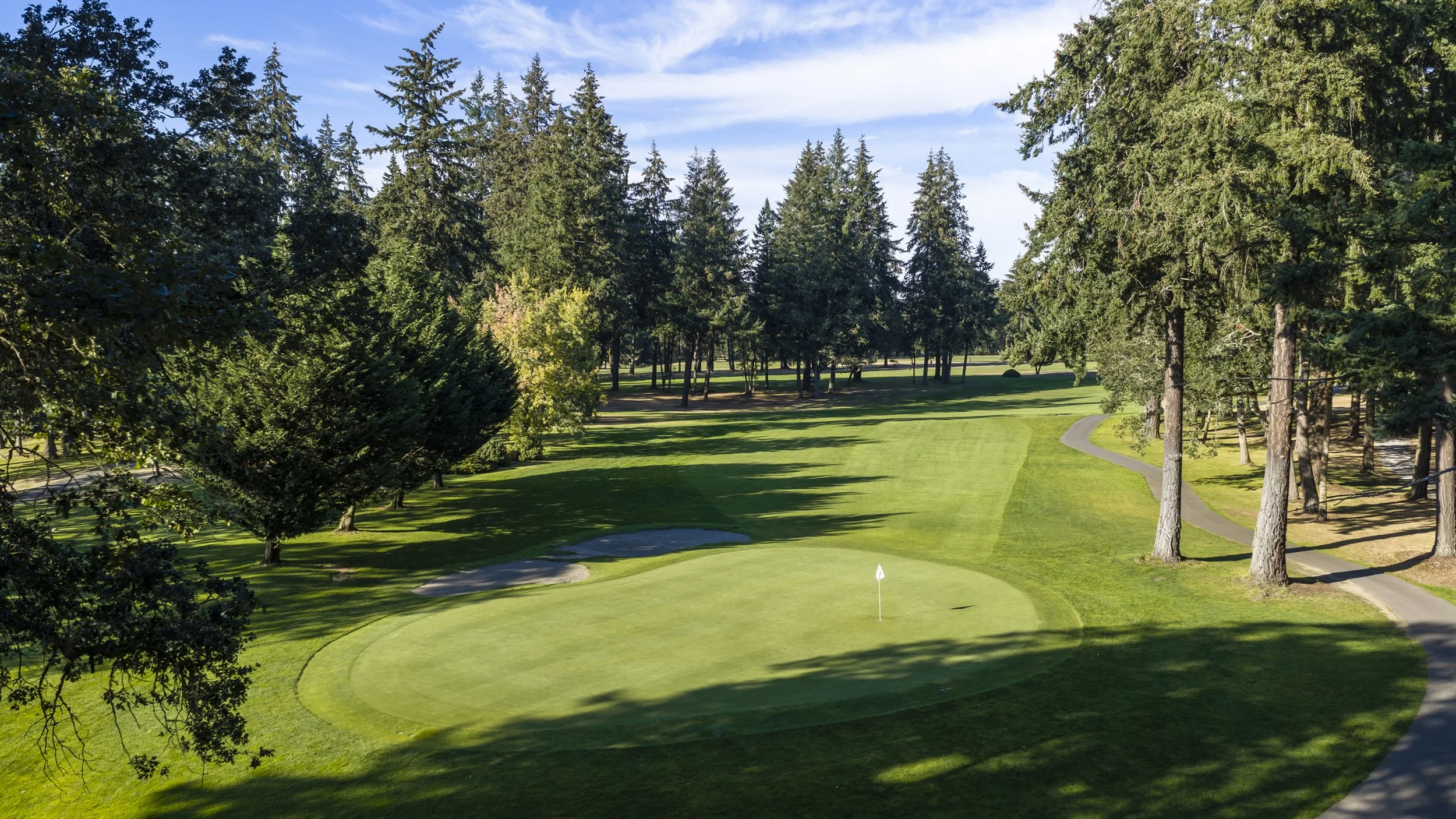 Hole 7 at American Lake Veterans Golf Course, with the flag on the green and a curving cart path.