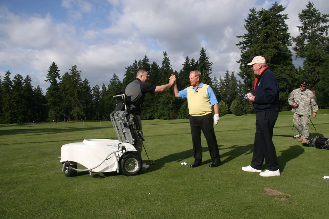A man beside a golf cart high-fives another man on the course.