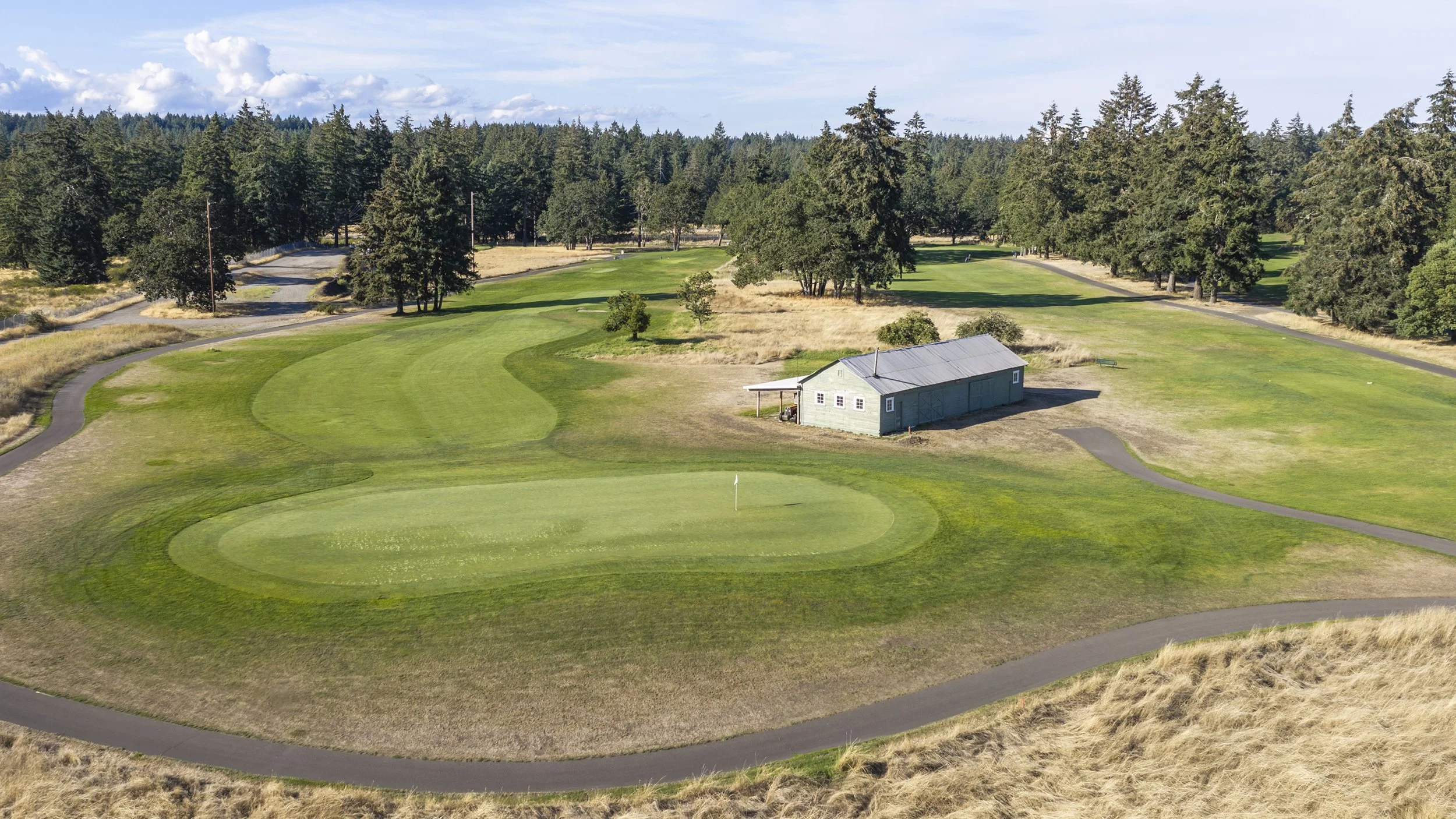 Hole 16 at American Lake Veterans Golf Course, a fairway with a small building among the trees.