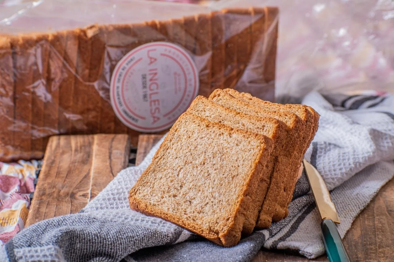 Tres rebanadas de pan integral sobre un paño, con una bolsa de pan en el fondo.