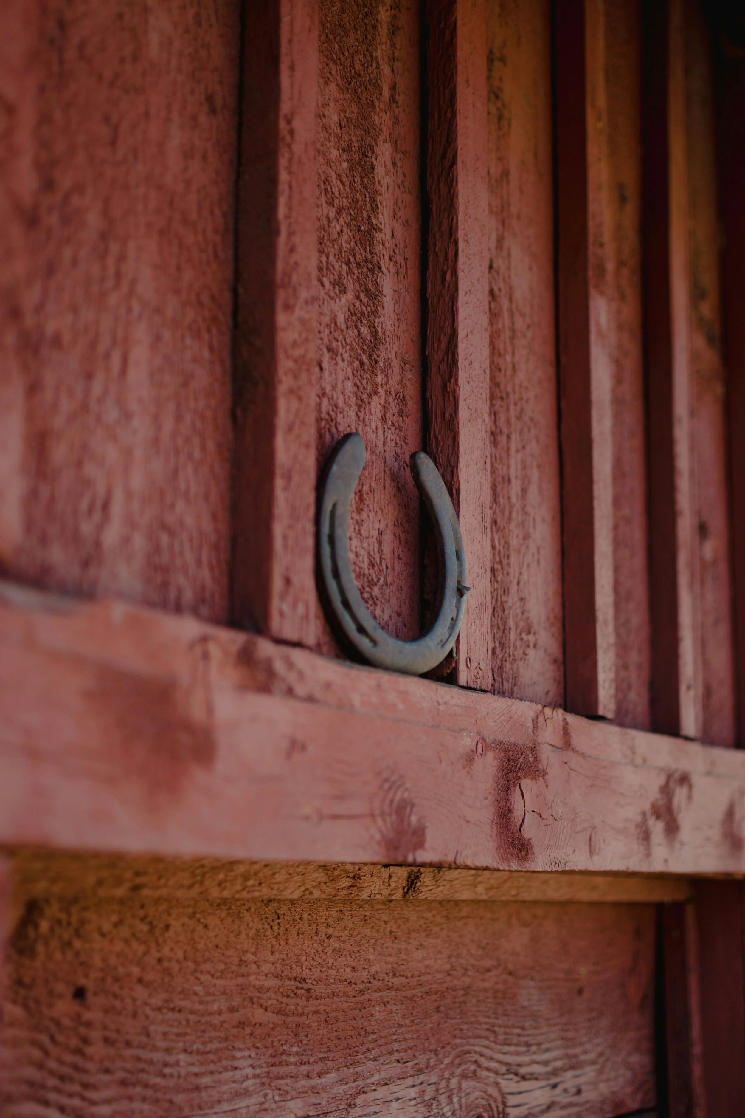 Close-up of a red wooden barn with a horseshoe attached to the boards.
