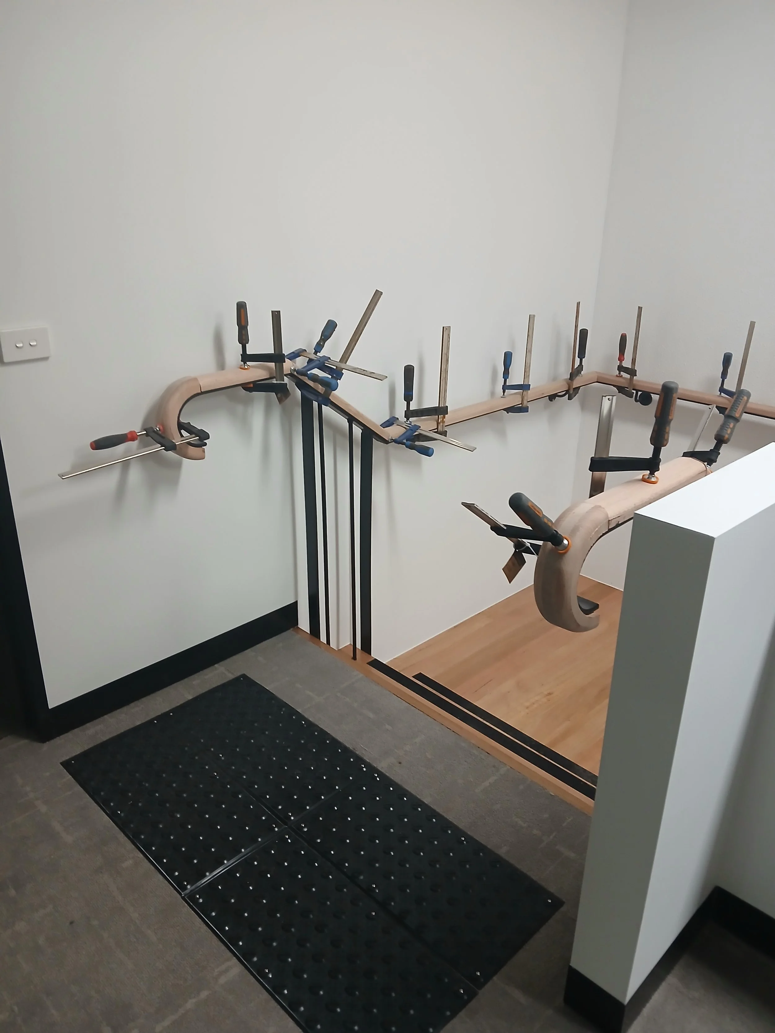 commercial stair timber handrail being fitted on steel balustrade.jpg