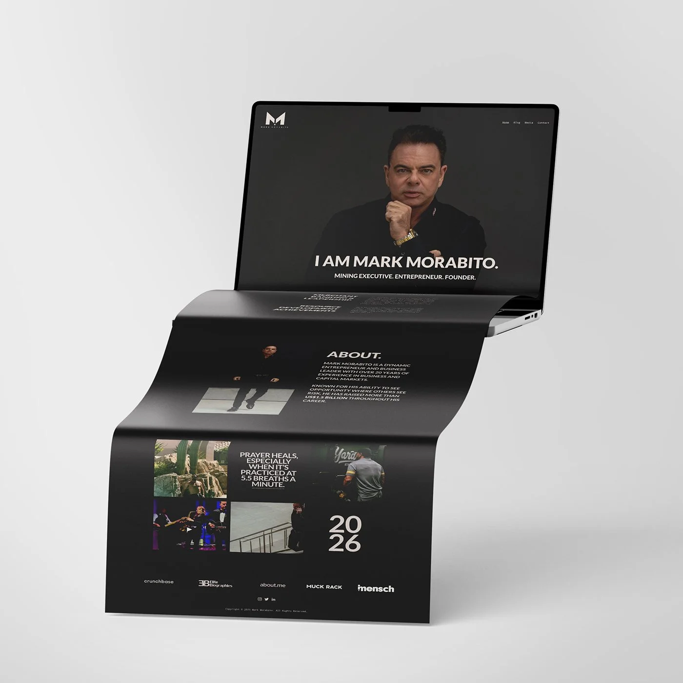 A laptop with a webpage about Mark Morabito, showing a photo of him and sections of text describing his background and achievements, with part of the webpage appearing as a scrolling strip.