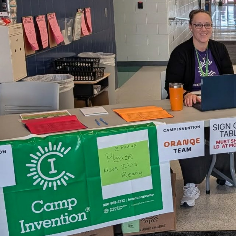 The director of Camp Invention - Ankeny Iowa sits at a table registering campers